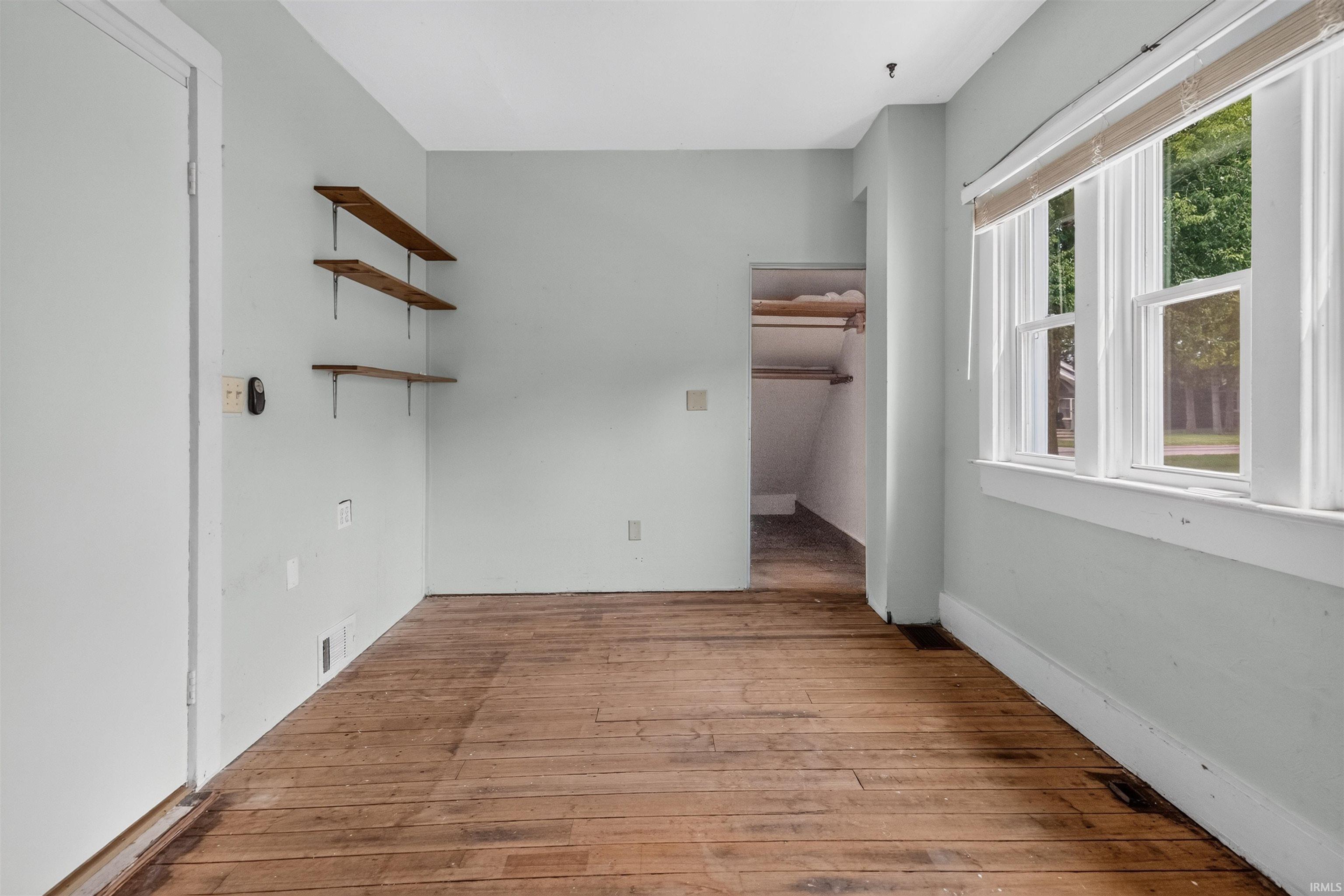Room featuring wood-finish flooring, light-toned walls, and a window with natural light