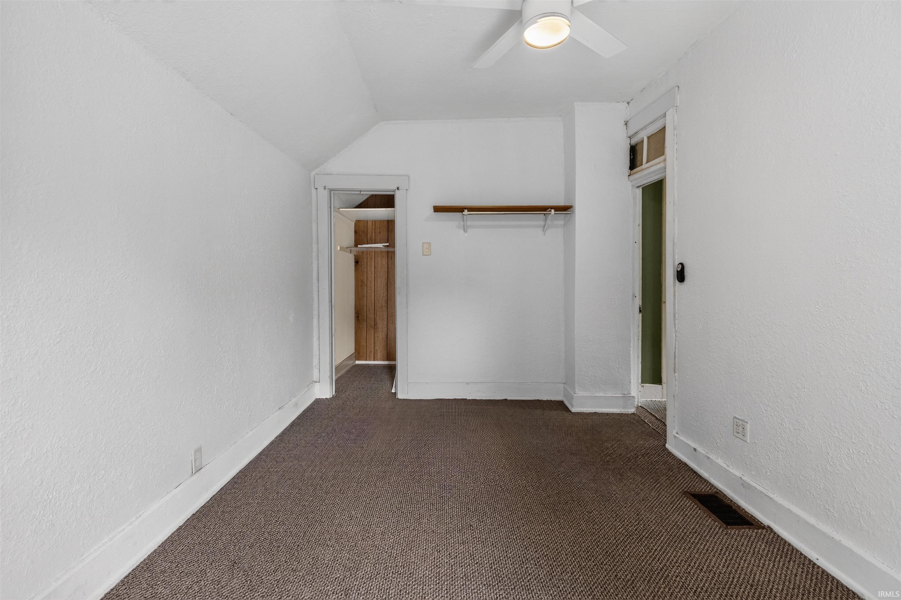Carpeted room featuring a ceiling fan, baseboard trim, and a built-in closet with shelving