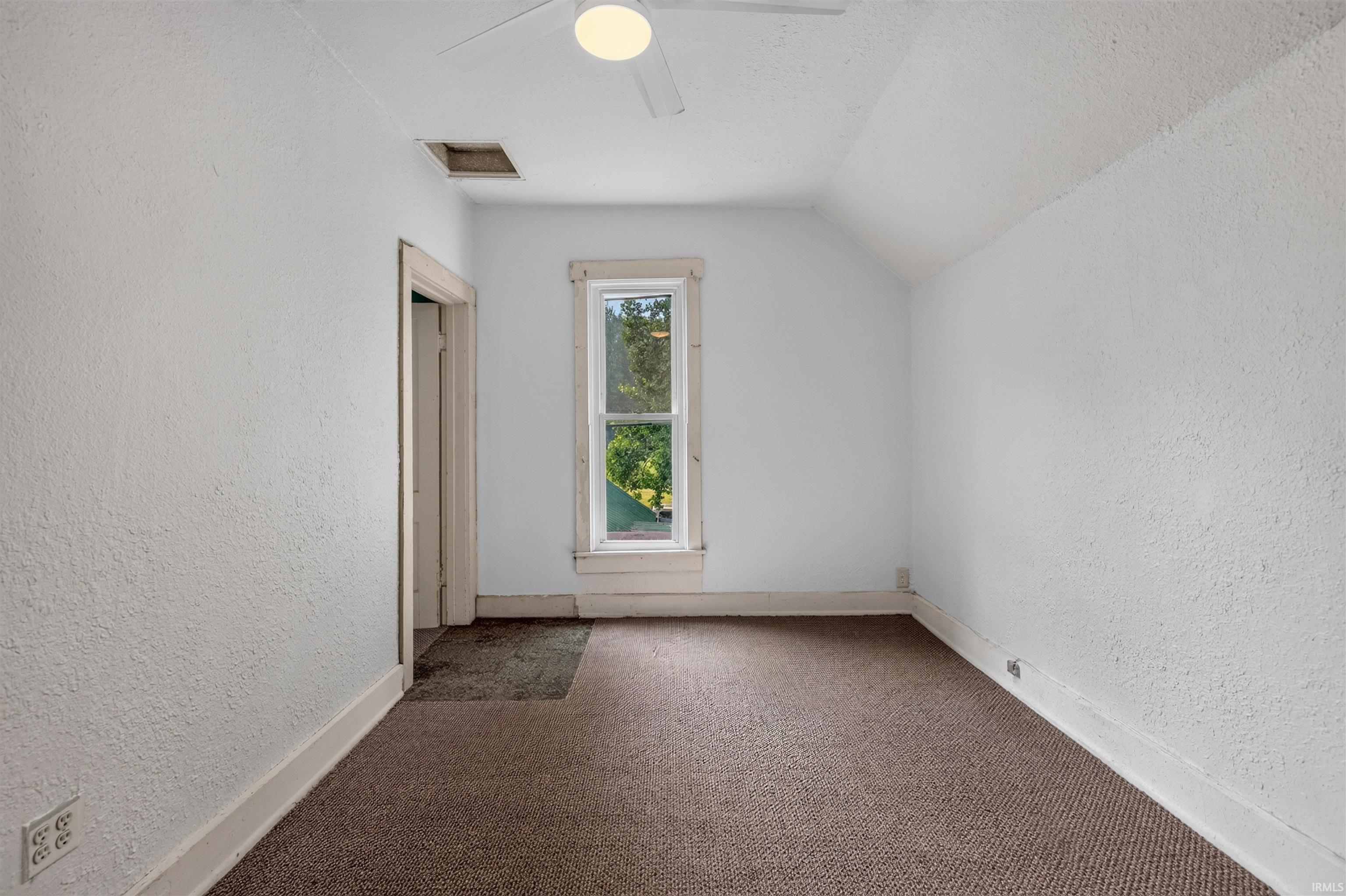 Room featuring a single-pane window with white trim, a ceiling fan, and sloped ceiling