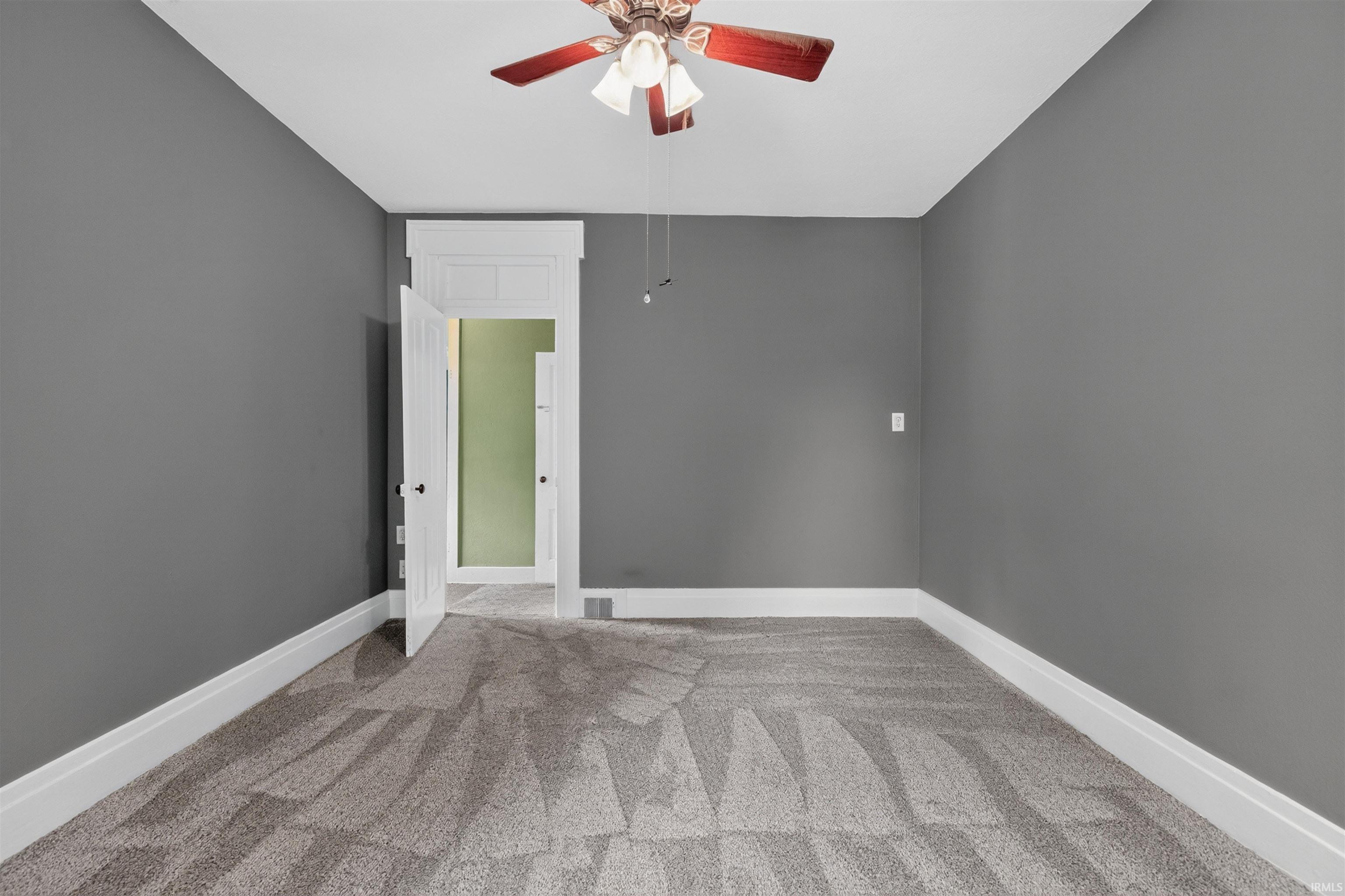 Room featuring textured gray carpeting, dark gray walls, and white baseboards