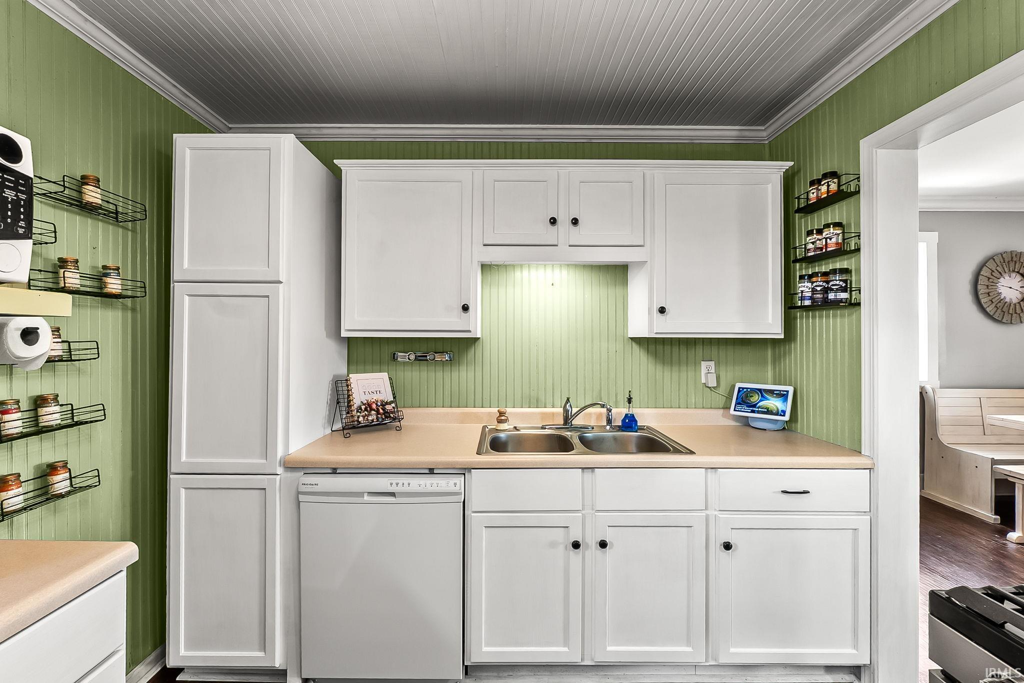 Kitchen featuring white shaker cabinetry, light-toned countertops, and a double basin stainless steel sink
