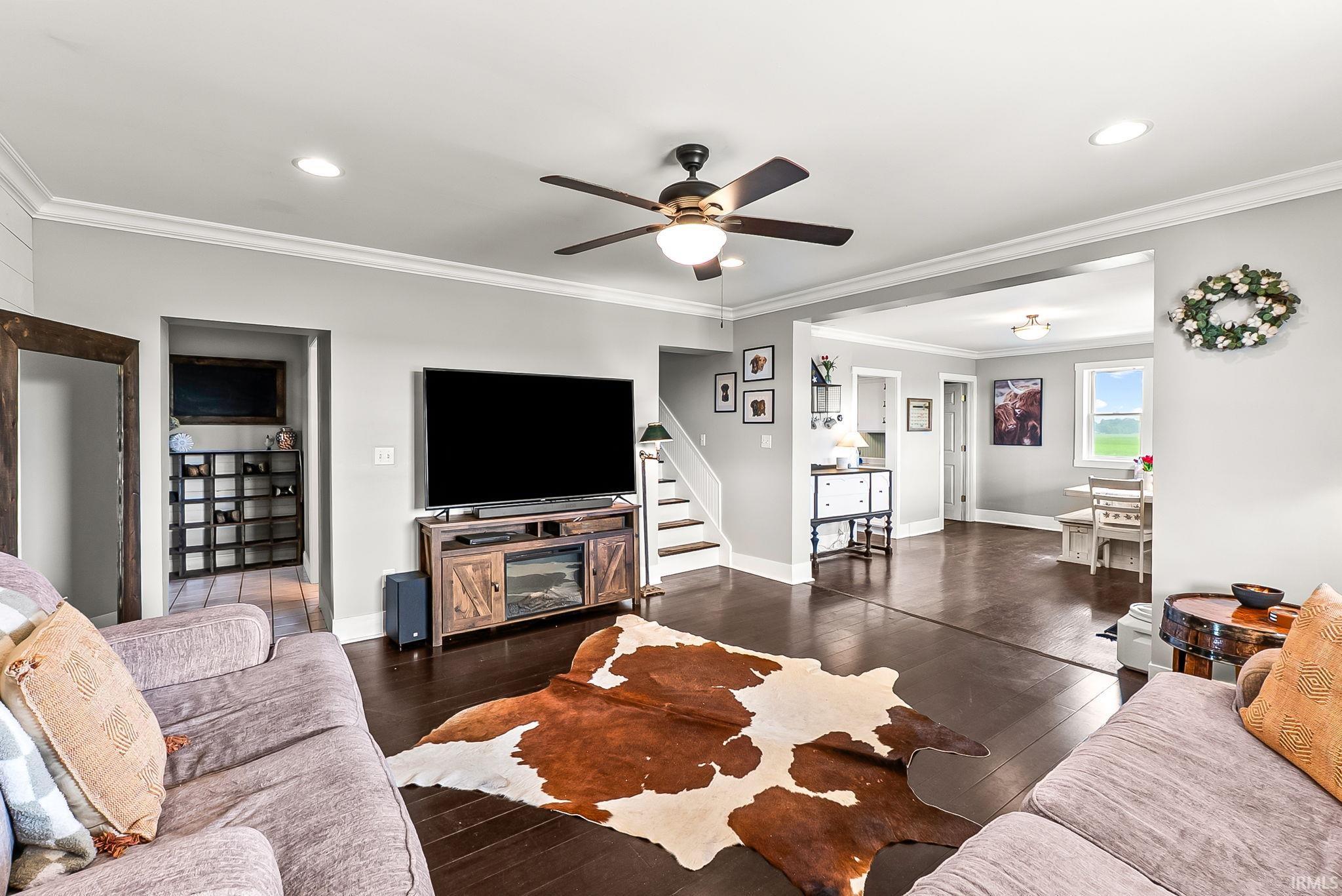 Expansive living area featuring rich wood-finish flooring, a contemporary ceiling fan, and recessed lighting