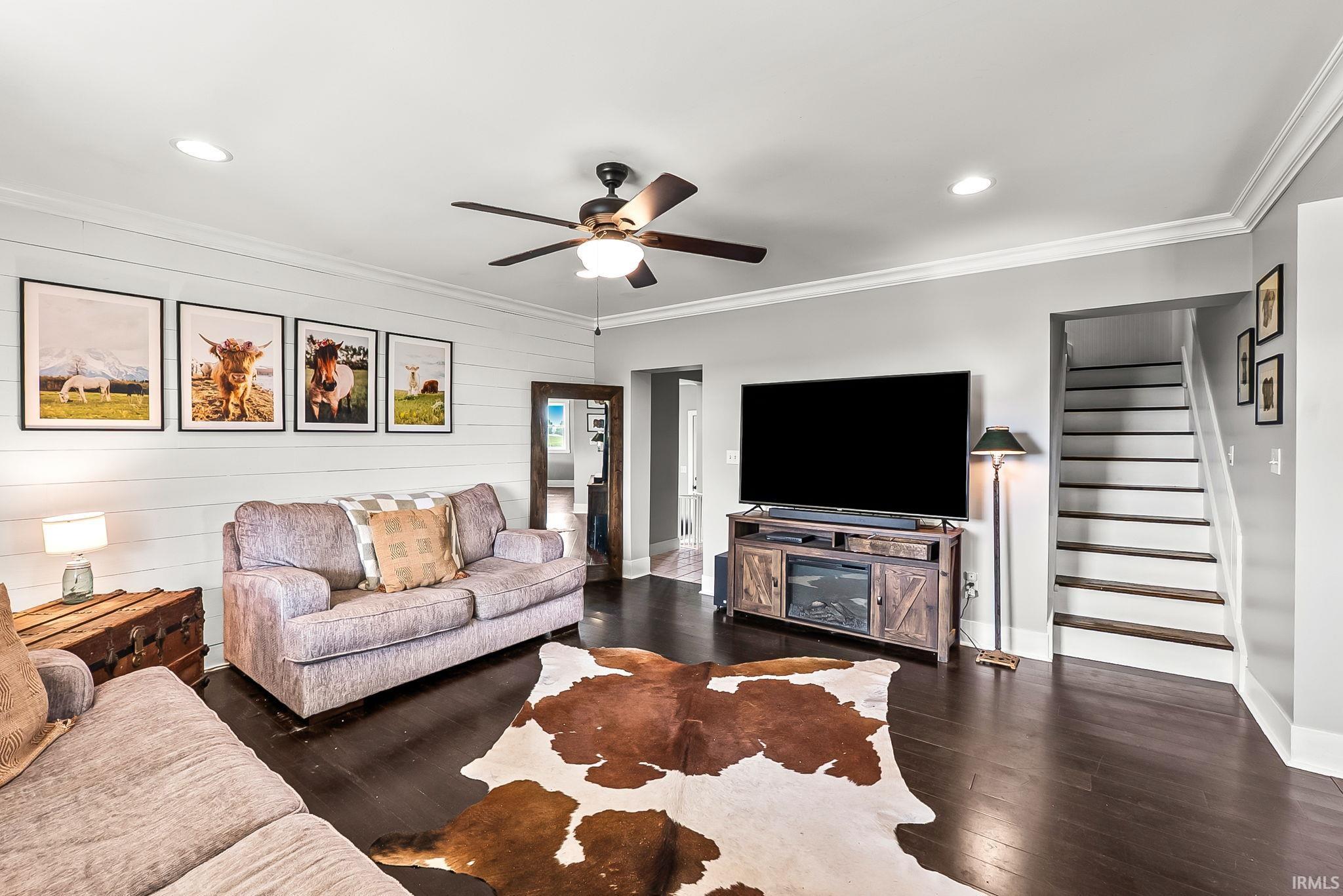 Living area featuring dark wood-finish flooring, a shiplap accent wall, recessed lighting, and a ceiling fan