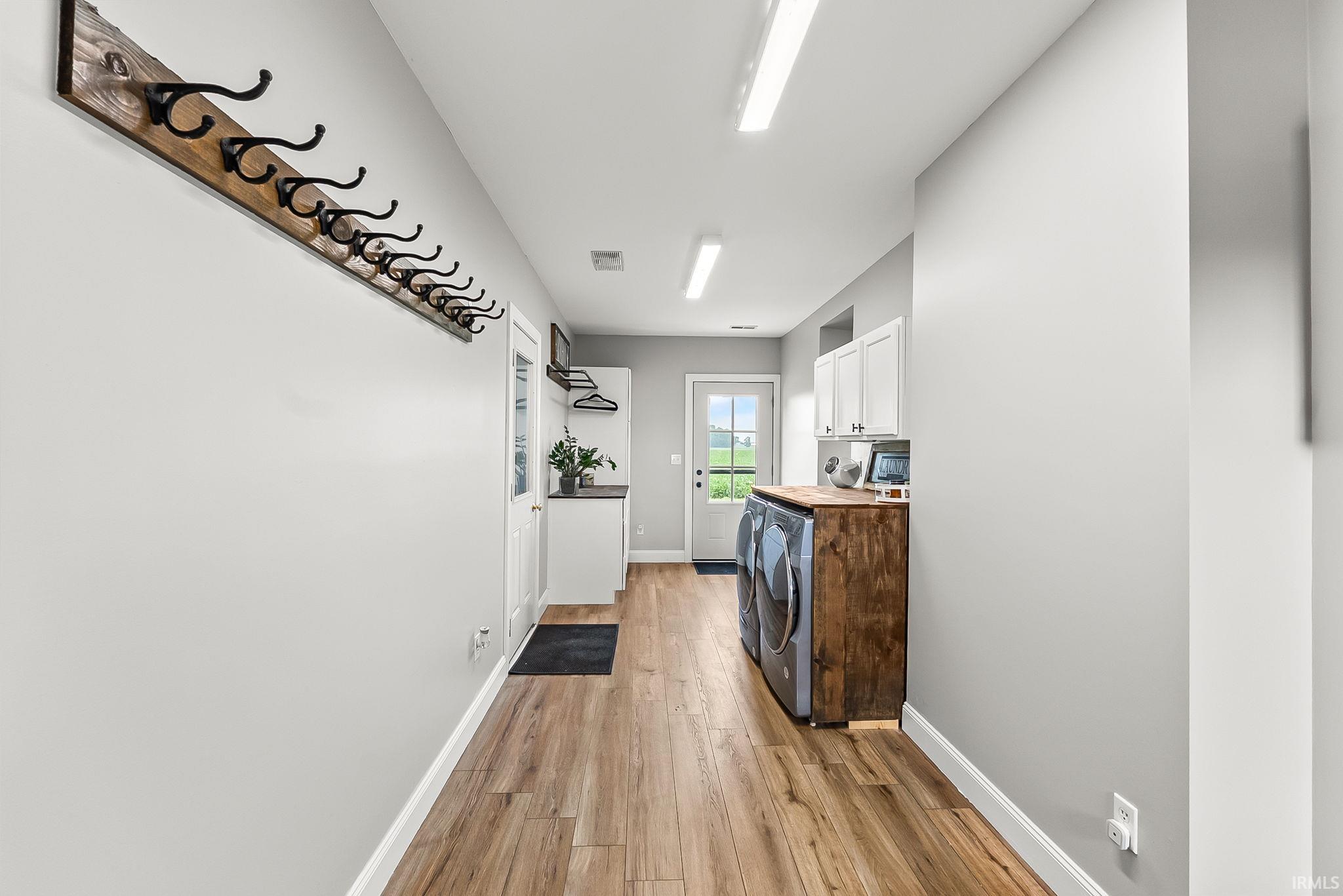 Dedicated laundry area featuring wood-finish flooring and a white built-in cabinetry