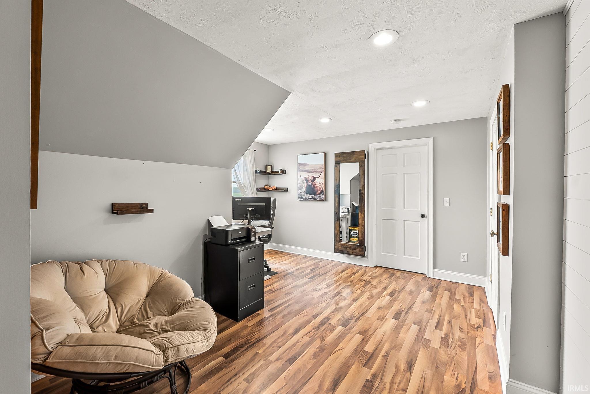 Versatile bonus room featuring wood-finish flooring, recessed lighting, and a white paneled door