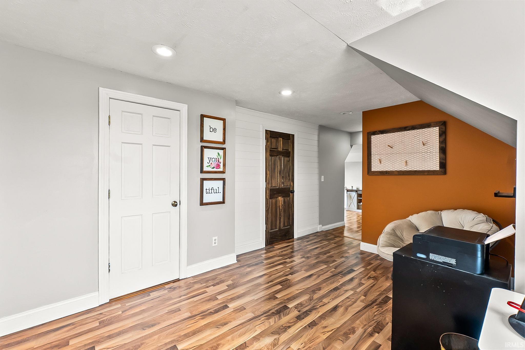Interior space featuring wood-finish flooring, recessed lighting, and a white six-panel door