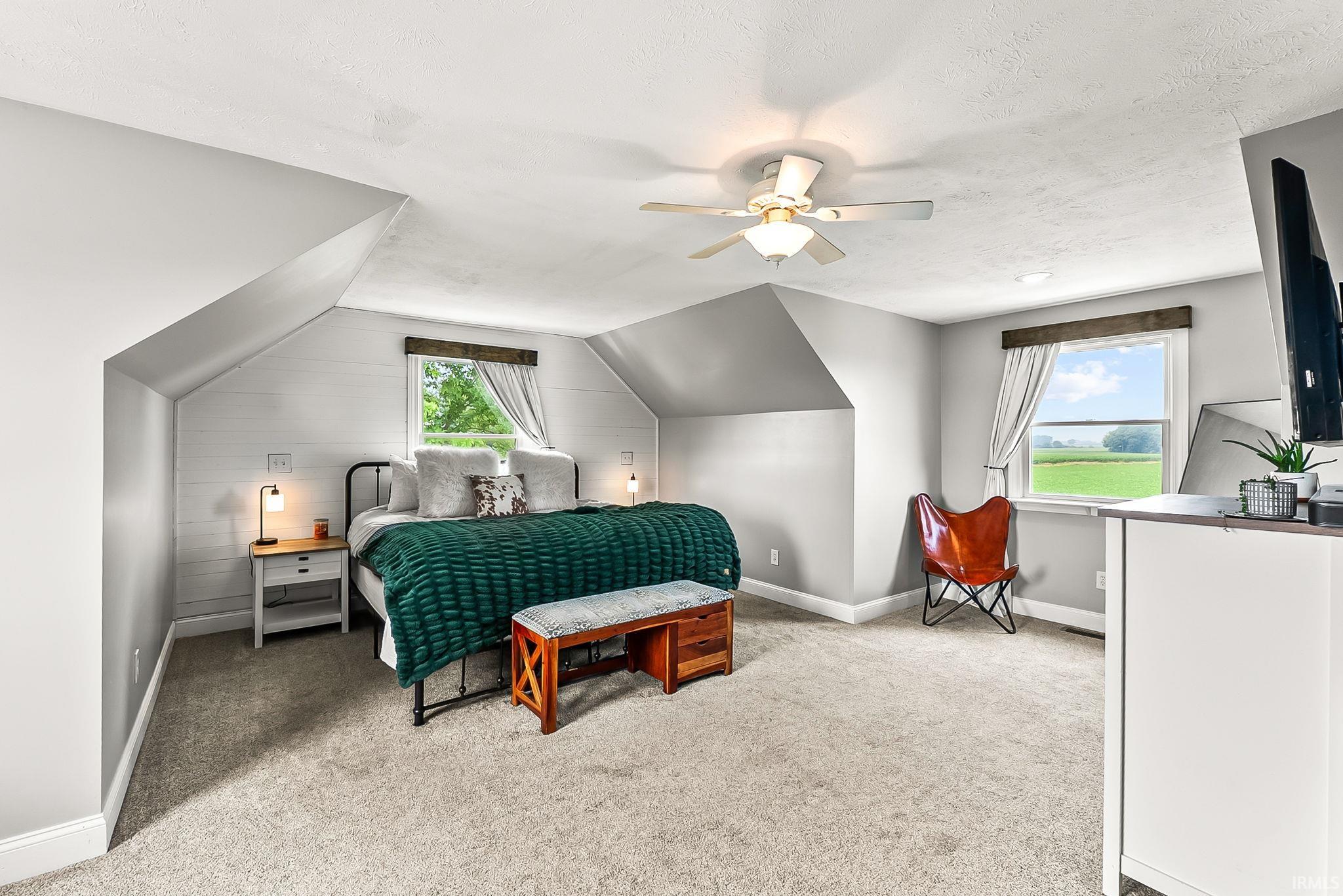 Carpeted room featuring a ceiling fan, sloped ceilings, and white paneled accent wall