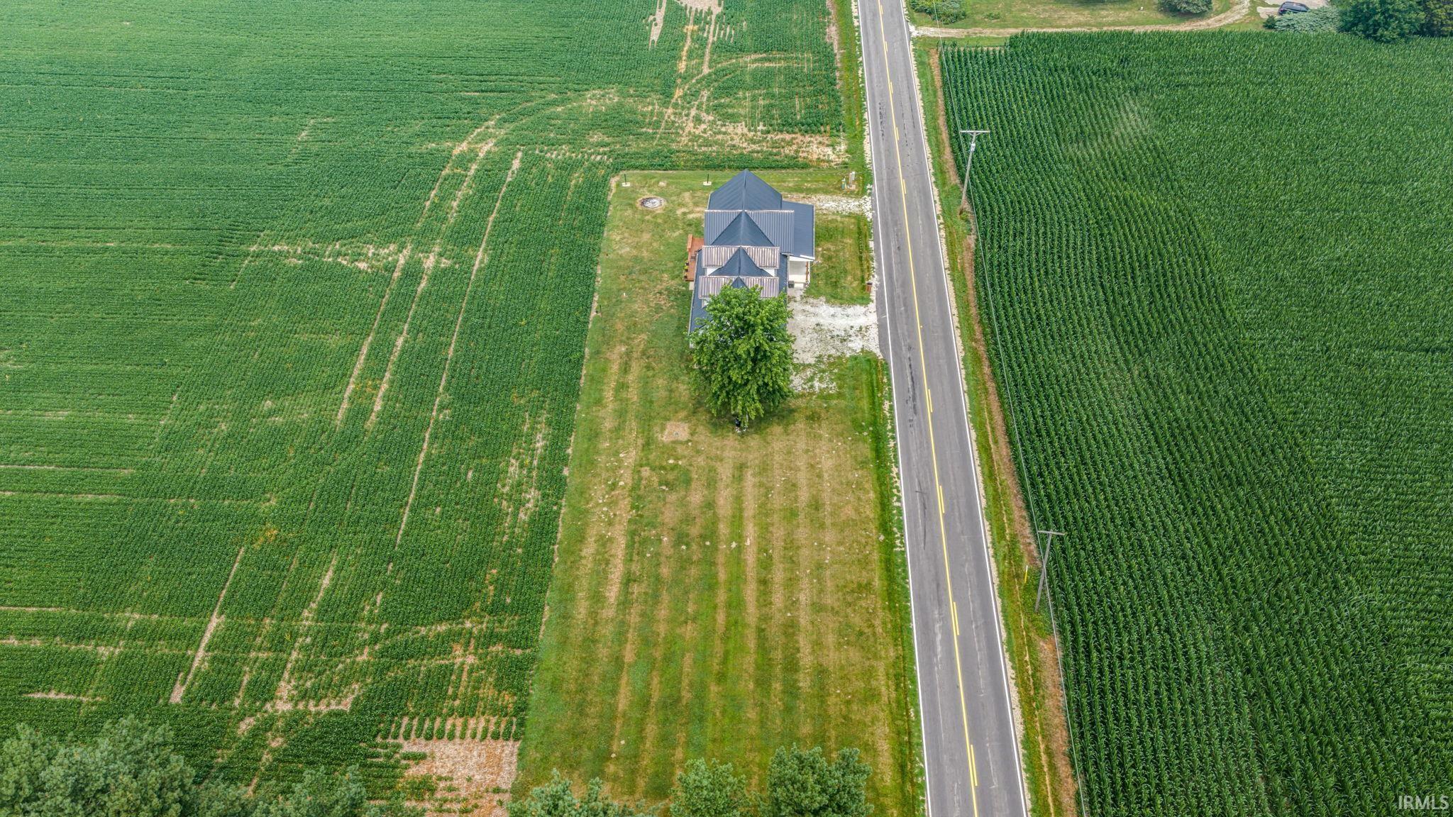 Aerial perspective showcasing a property featuring a multi-story residence with a dark-shingled roof
