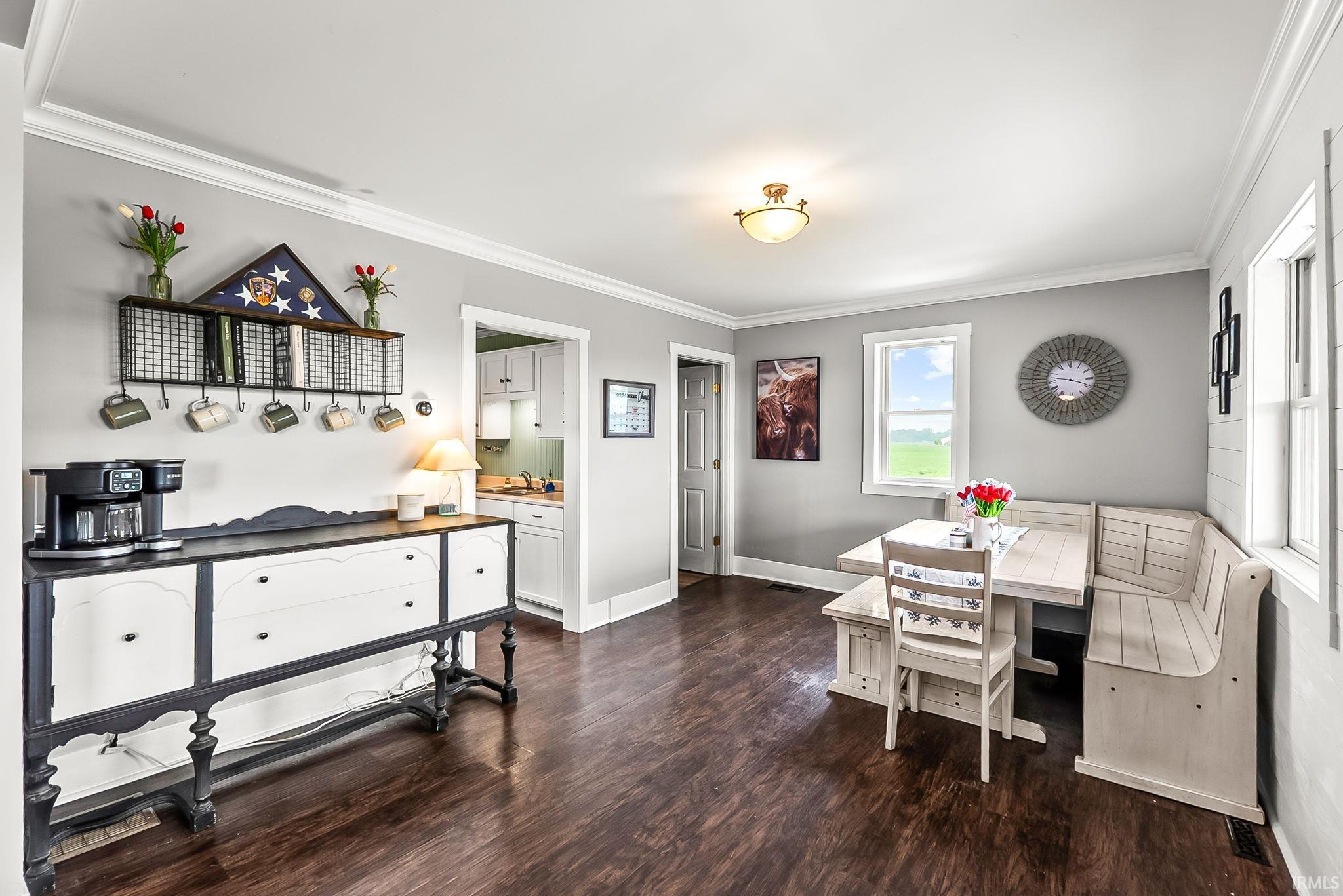 Dining area featuring wood-finish flooring, light gray wall paint, white trim, and a built-in banquette seating