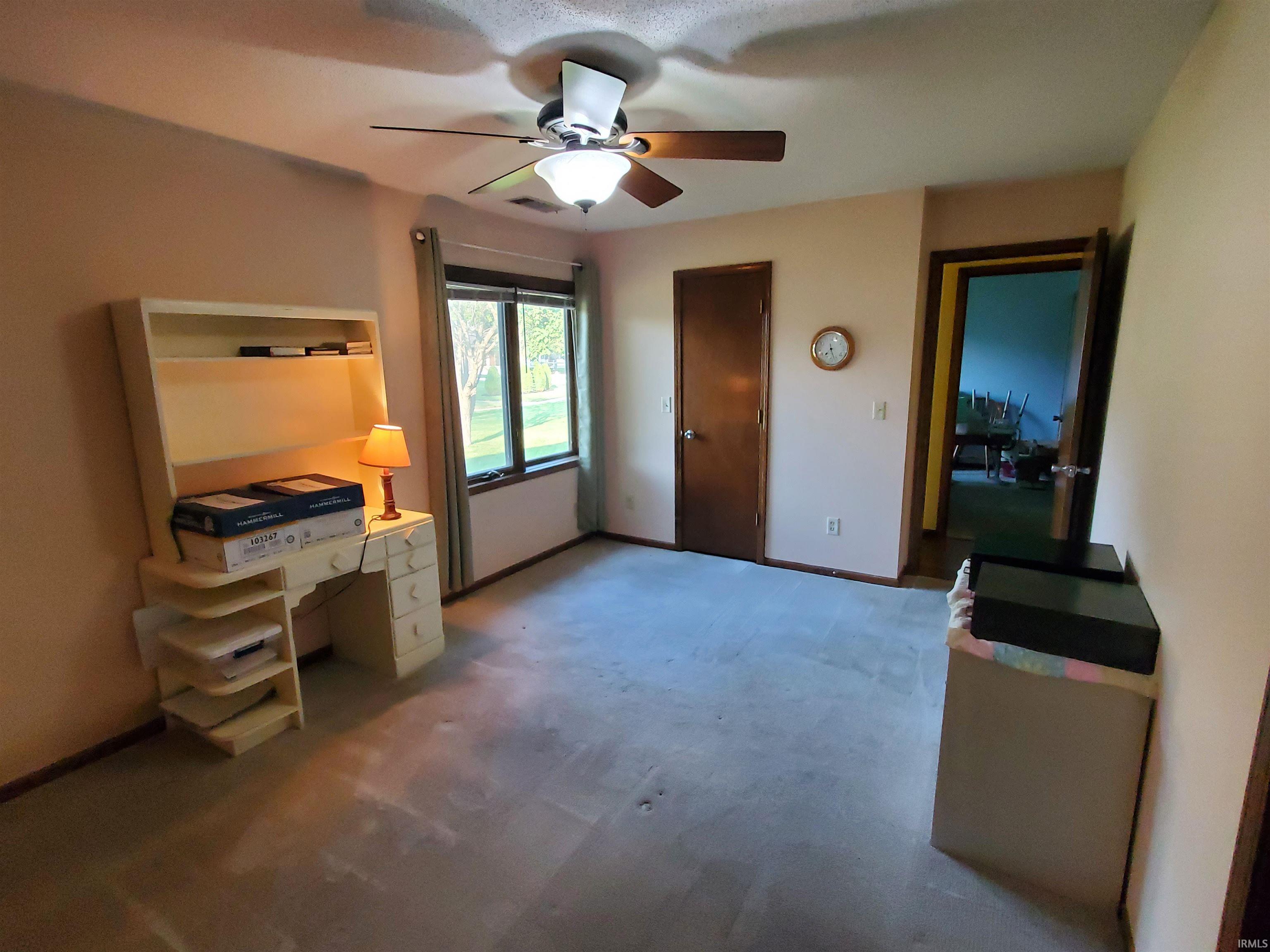 Room featuring a ceiling fan with light fixture, carpeted flooring, and a large window providing outdoor views