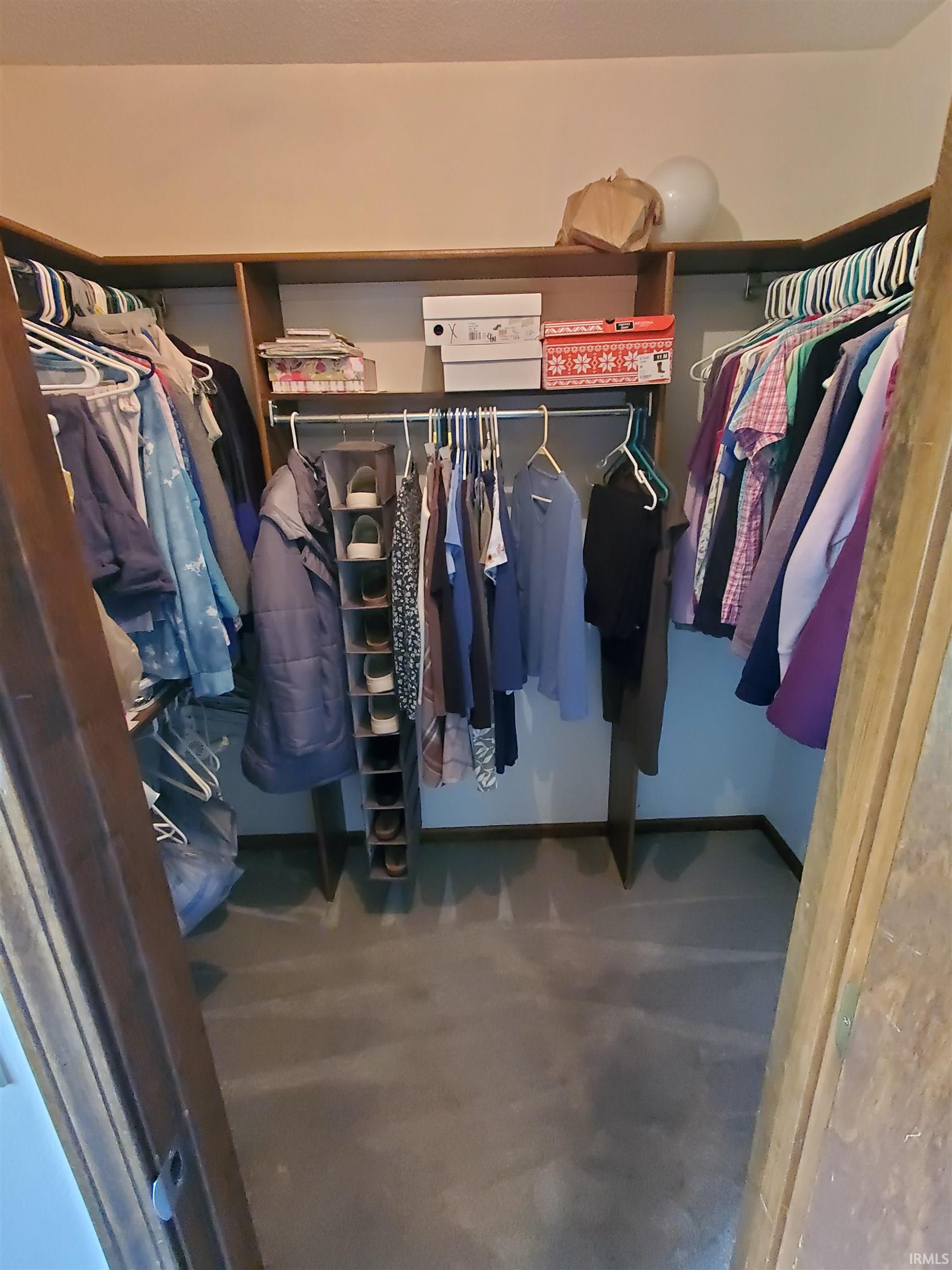 Walk-in closet featuring built-in shelving, multiple hanging rods, and neutral-toned carpeting