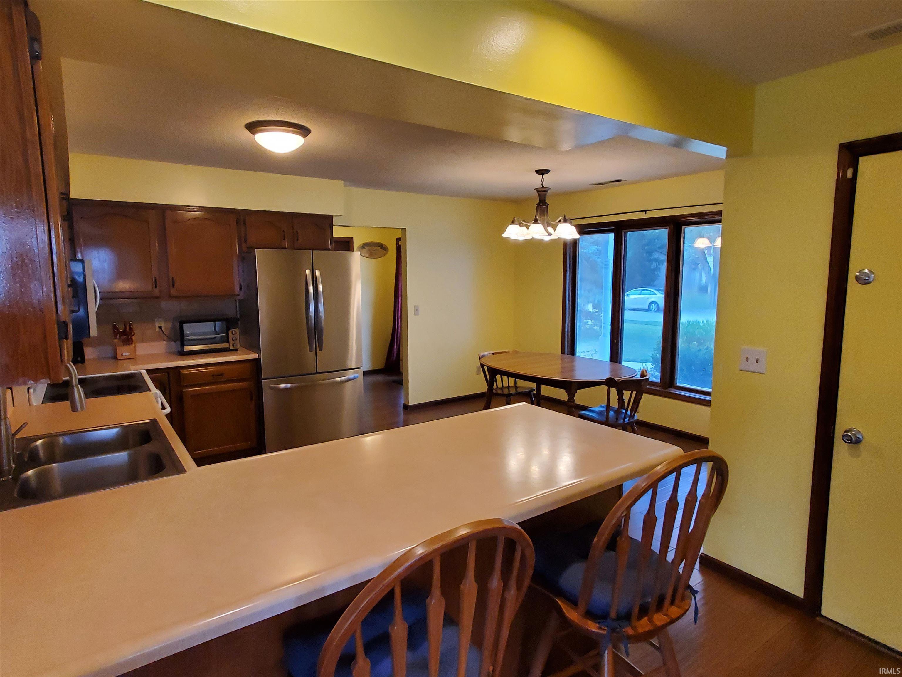 Kitchen featuring a breakfast bar with a solid surface countertop, stainless steel refrigerator, and wood cabinetry