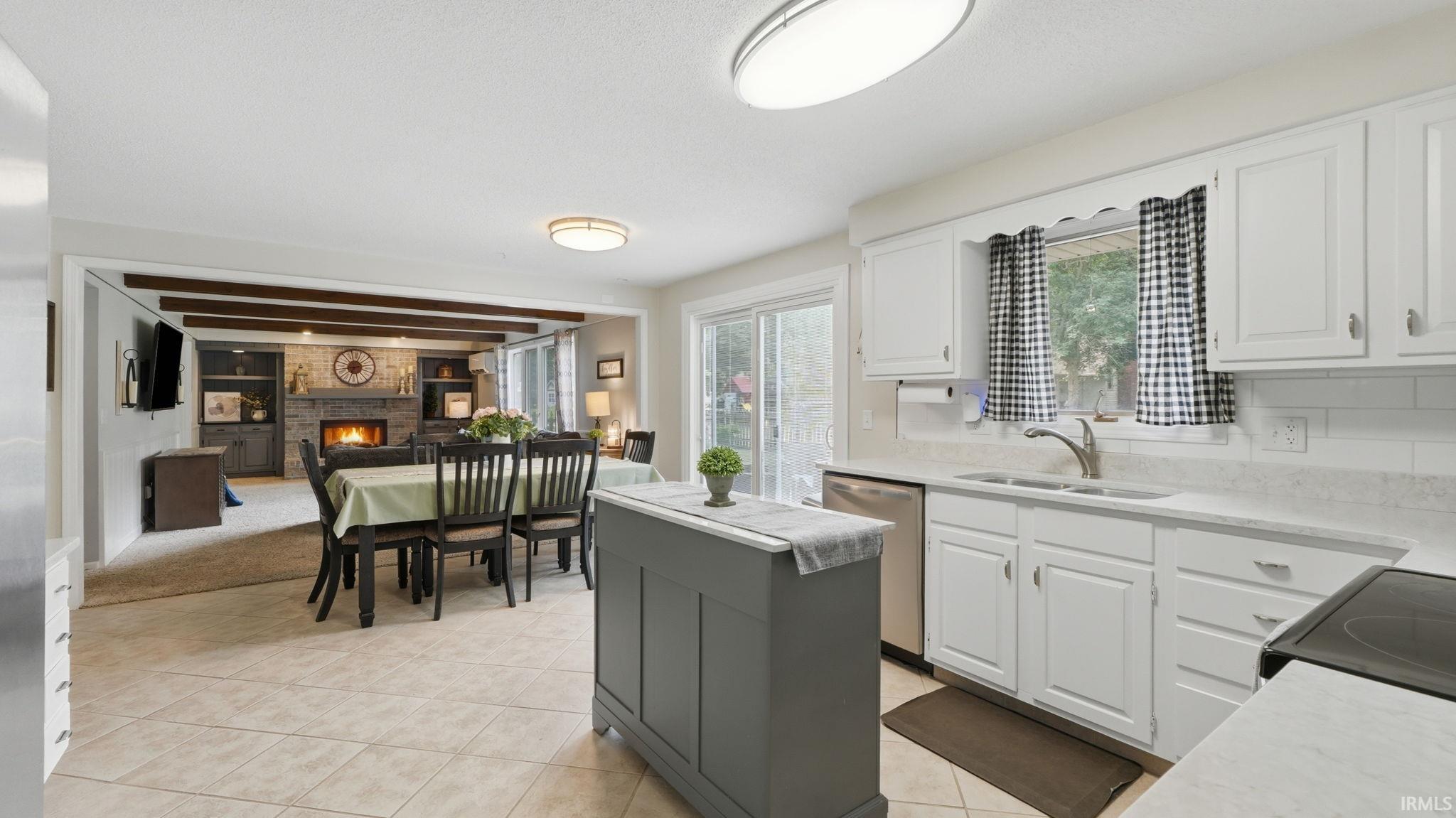 Open-concept kitchen featuring white cabinetry, light-toned countertops, and a white subway tile backsplash