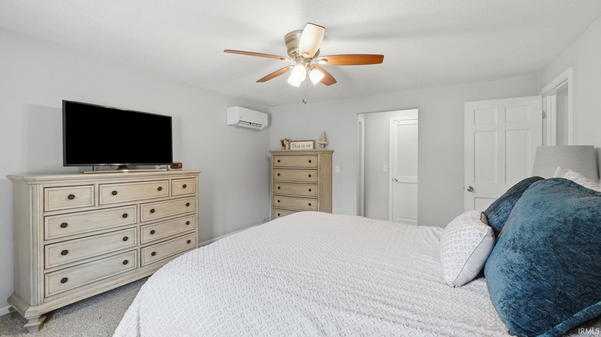 Spacious room featuring light gray walls, carpet flooring, a ceiling fan with integrated lighting, and multiple white interior doors