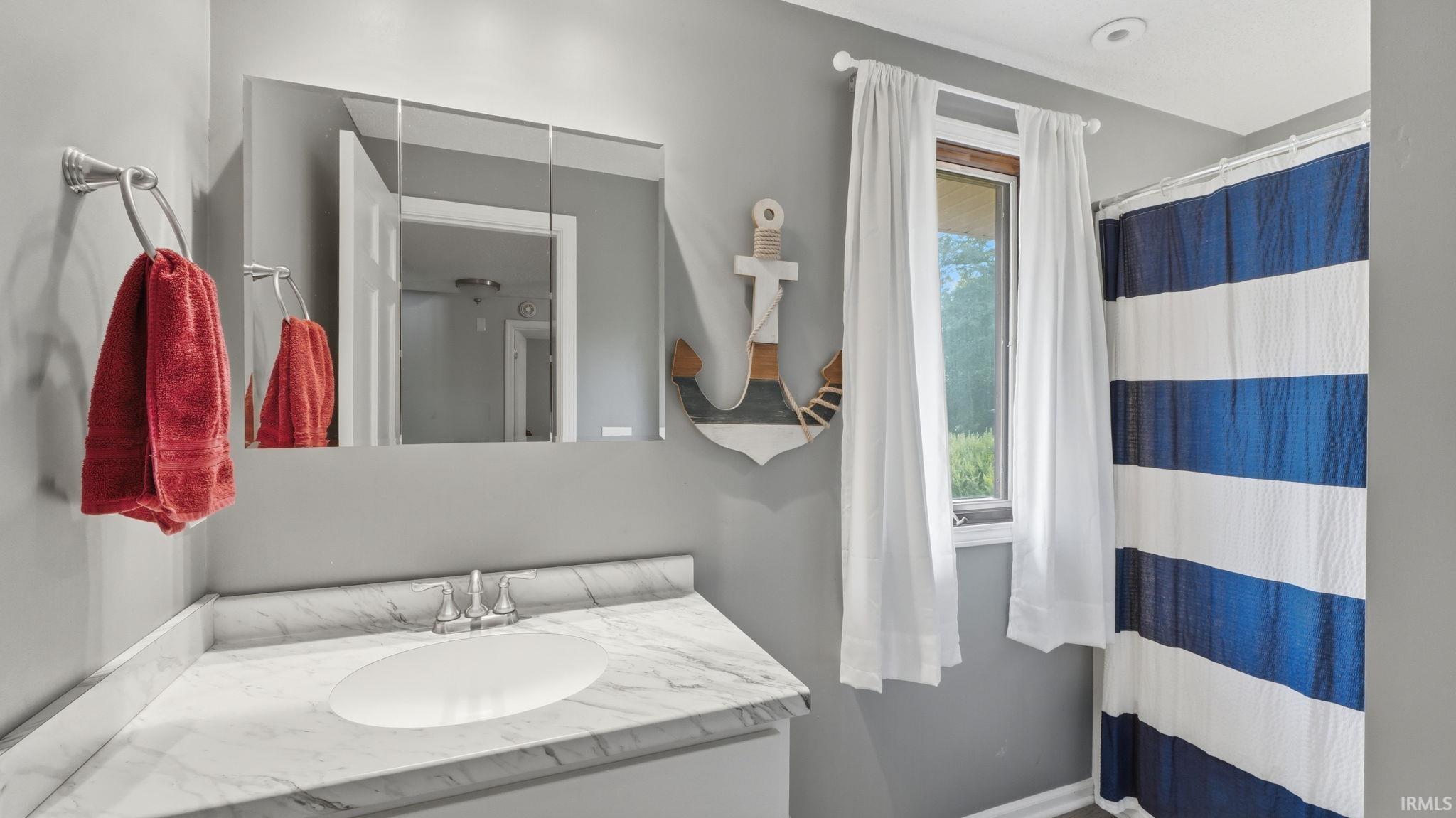 Bathroom vanity featuring a marble-finish countertop, undermount sink, and polished chrome faucet