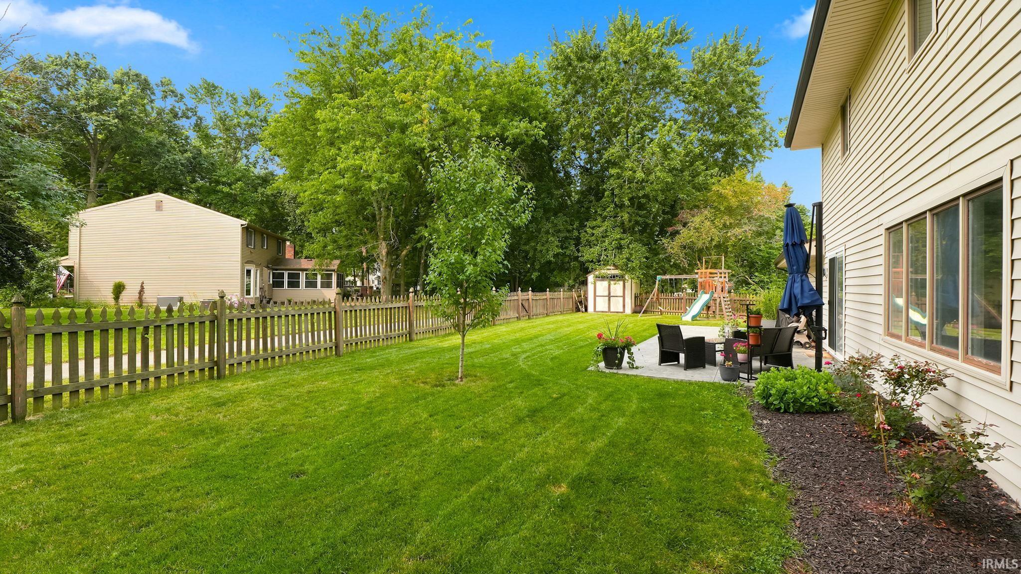 Expansive green lawn with a picket fence boundary and mature trees