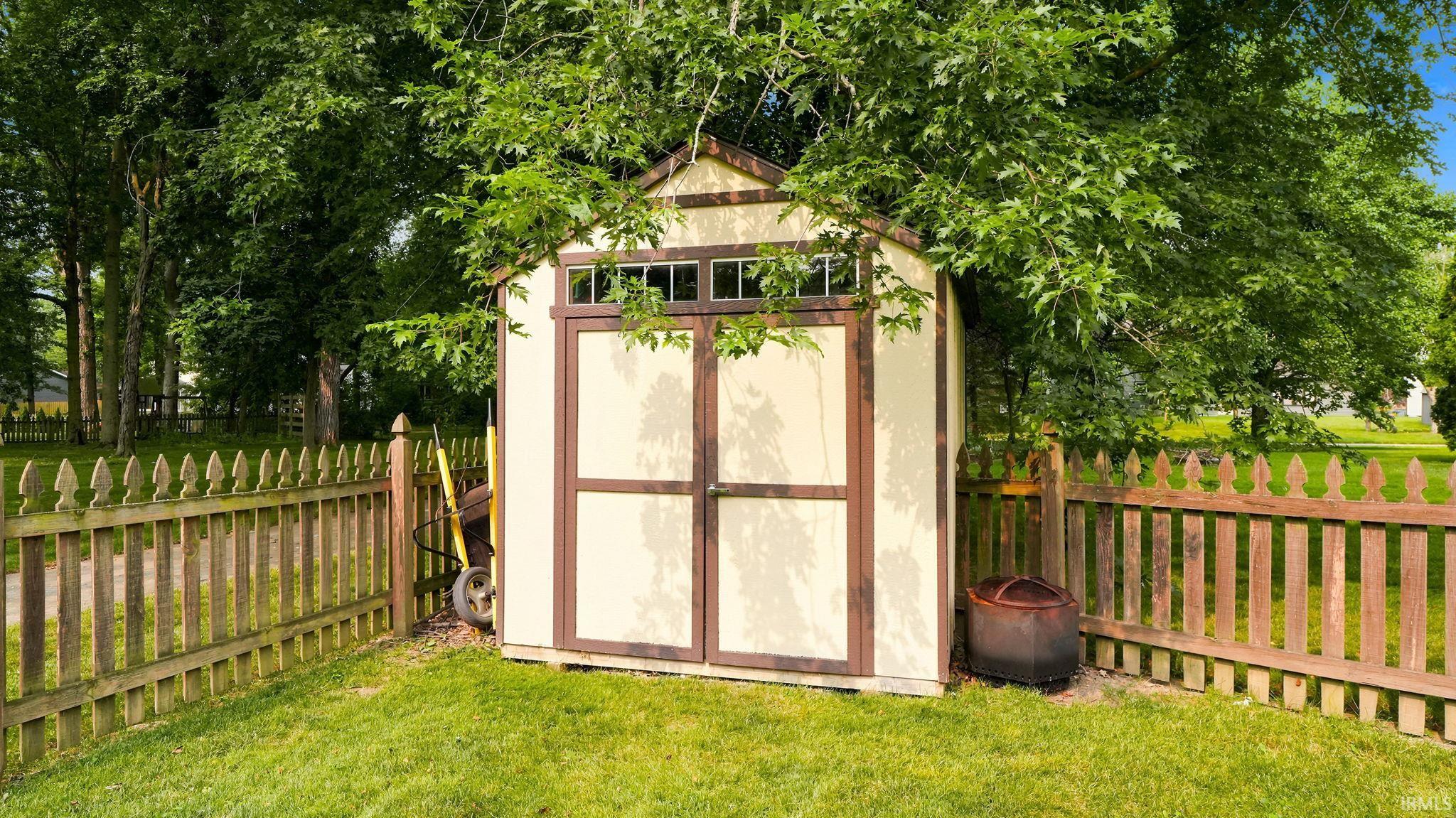 Utility shed featuring double doors, transom windows, and a gabled roof