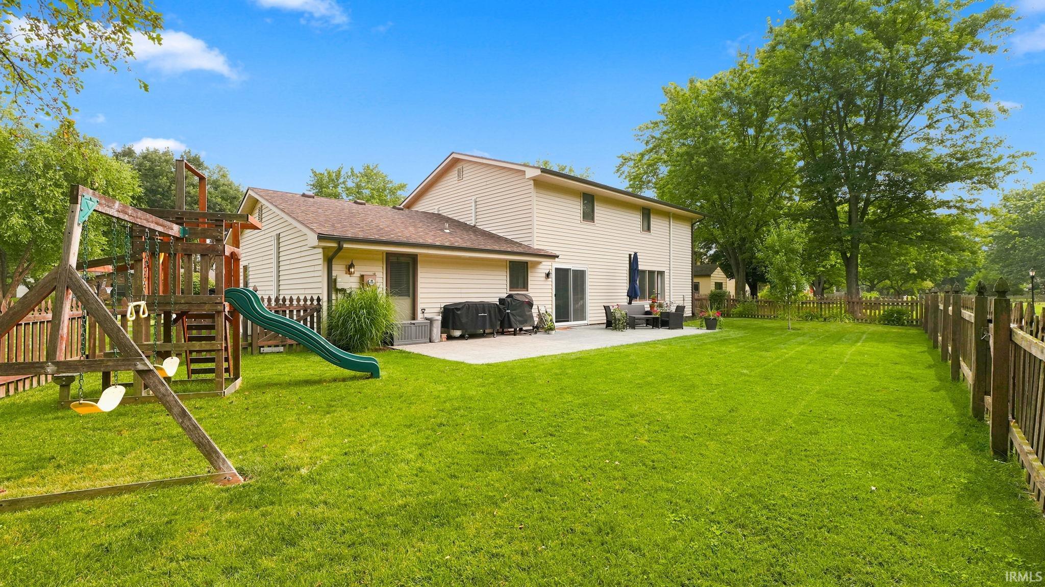 Expansive rear yard featuring a wide-open lawn, a substantial patio, and a privacy fence