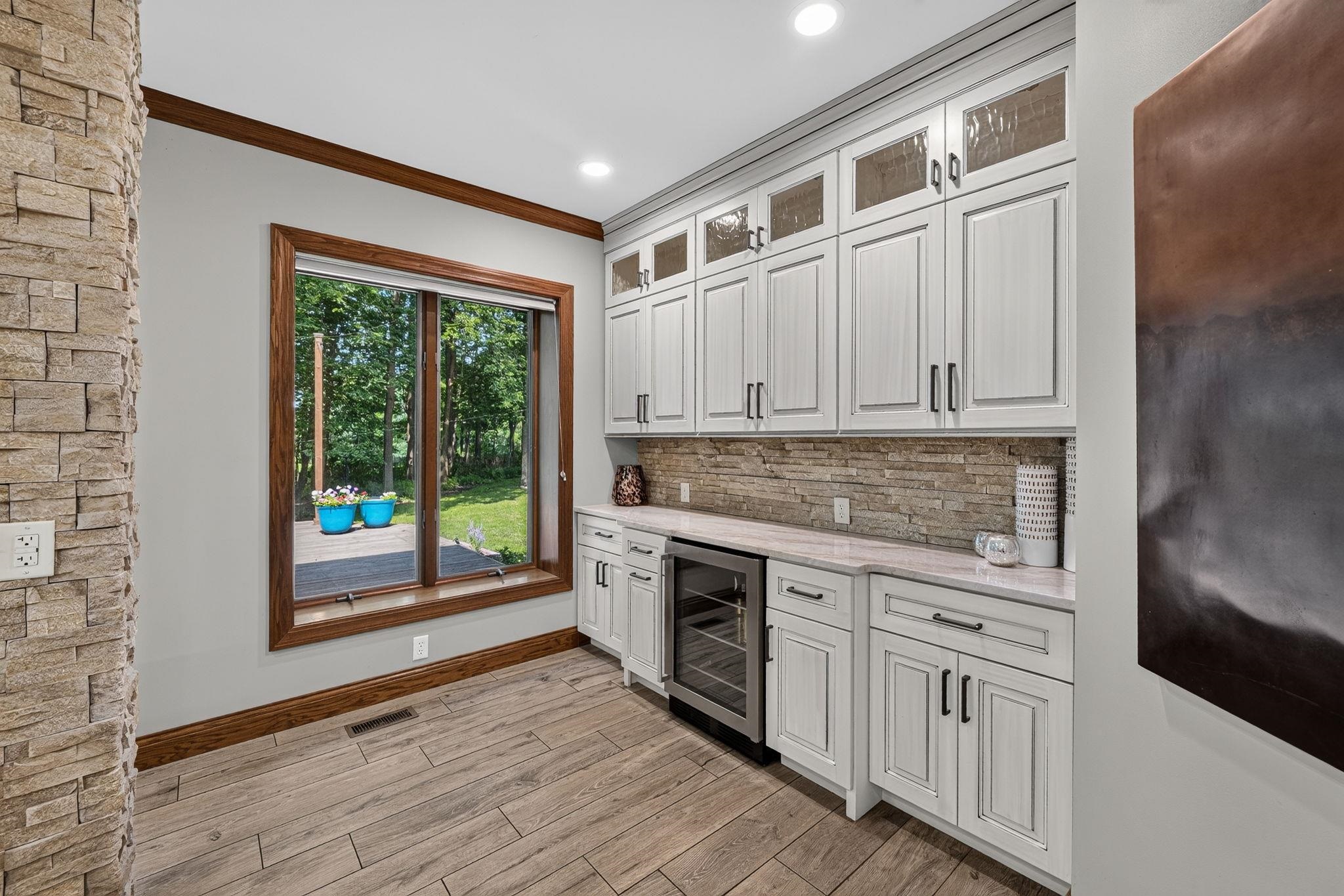 Built-in cabinetry with glass-front uppers and a beverage refrigerator
