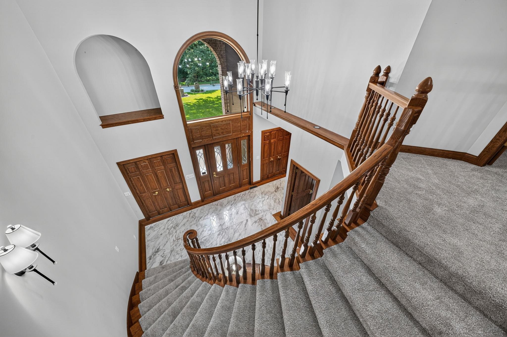 Grand foyer featuring a curved staircase with wood banister and carpeted treads