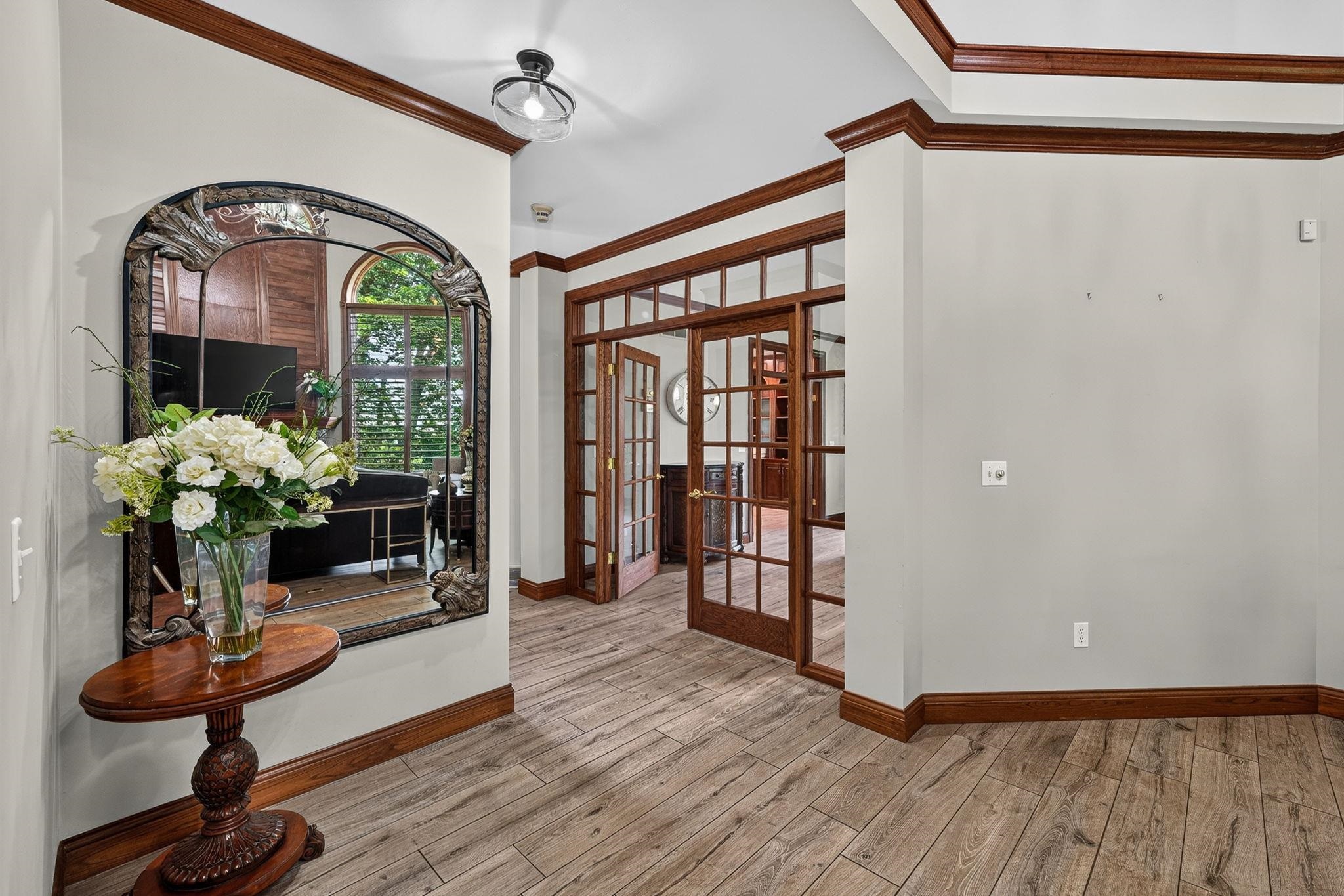 Hallway featuring wood-finish flooring, white walls, and dark wood trim