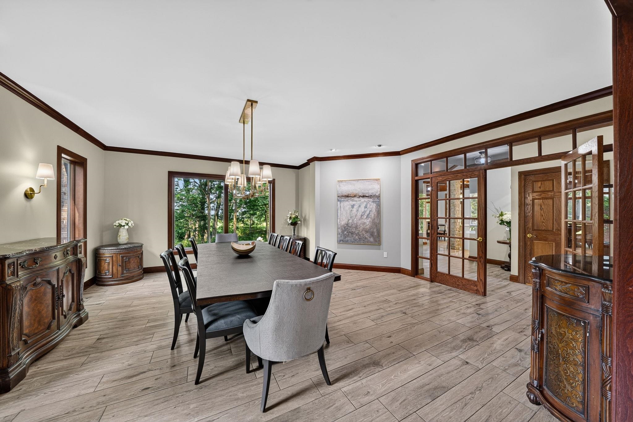 Spacious dining area featuring wood-finish flooring, crown molding, and a chandelier with multiple light sources