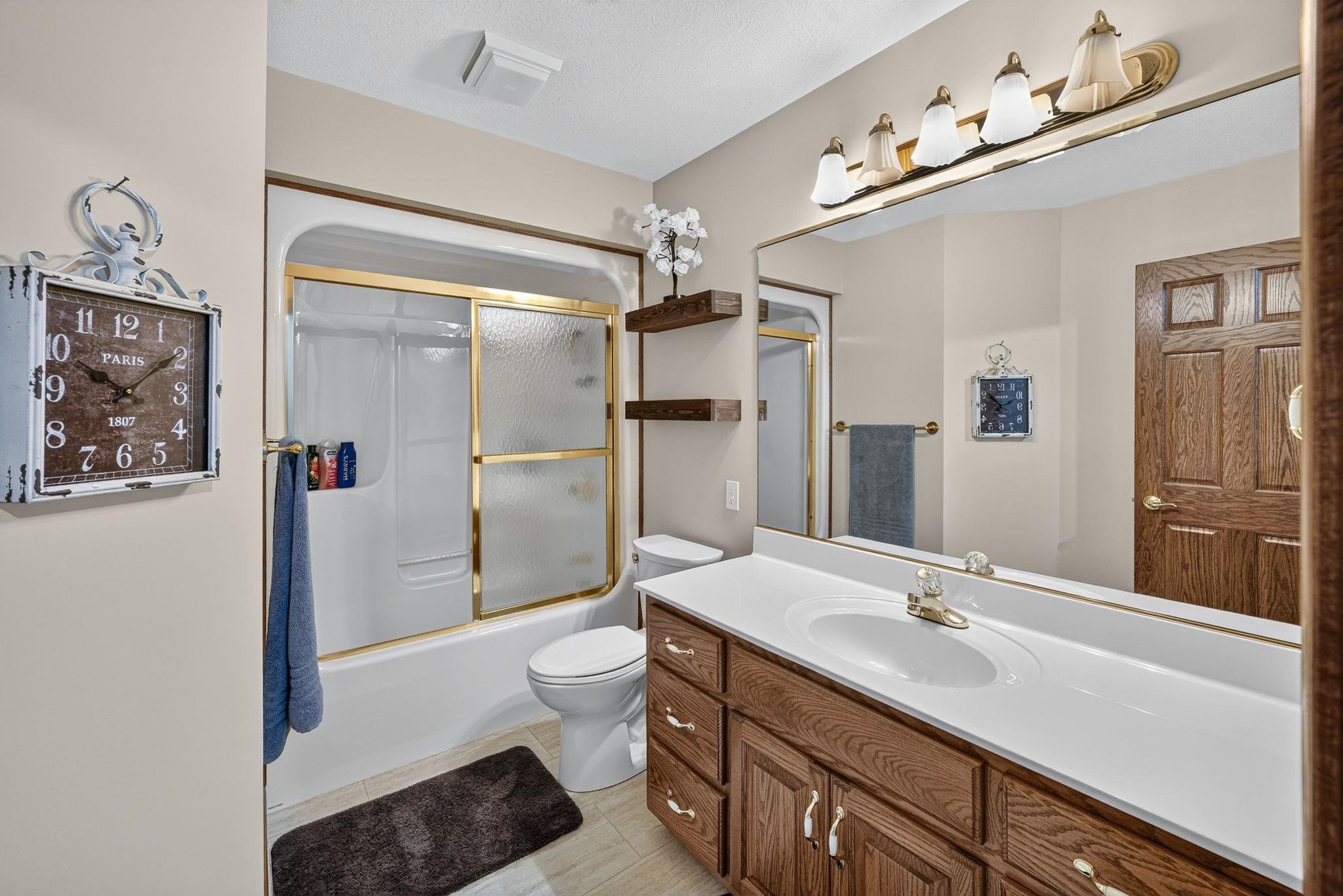 Bathroom featuring a vanity with a white countertop and wood-finish cabinetry, a full-width mirror, and a five-light fixture
