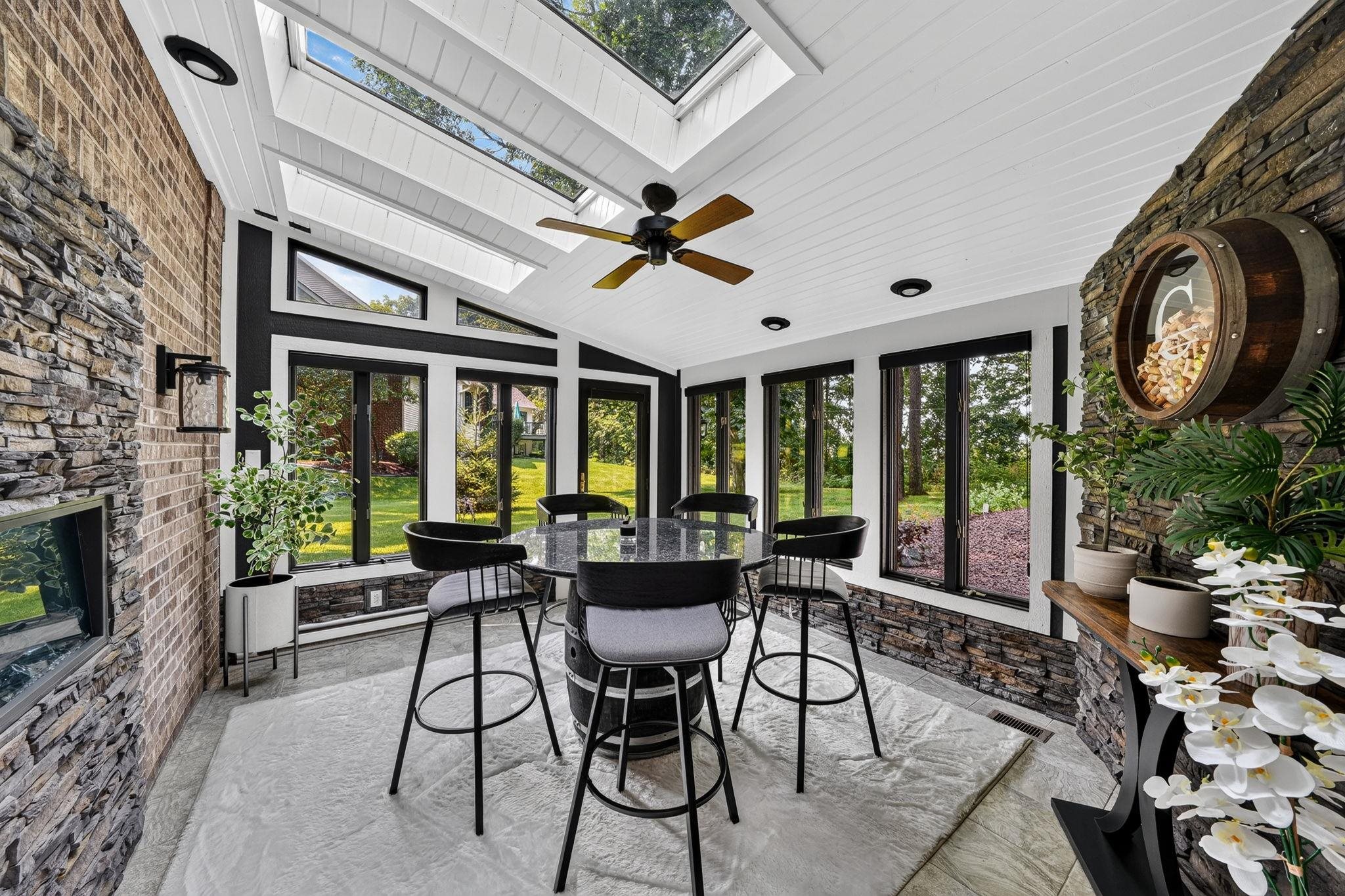 Sunroom with vaulted ceiling featuring multiple skylights and a ceiling fan
