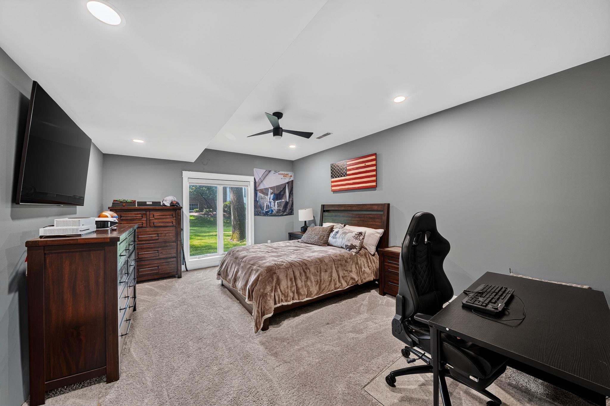 Carpeted room featuring a ceiling fan, recessed lighting, and a sliding glass door providing exterior access