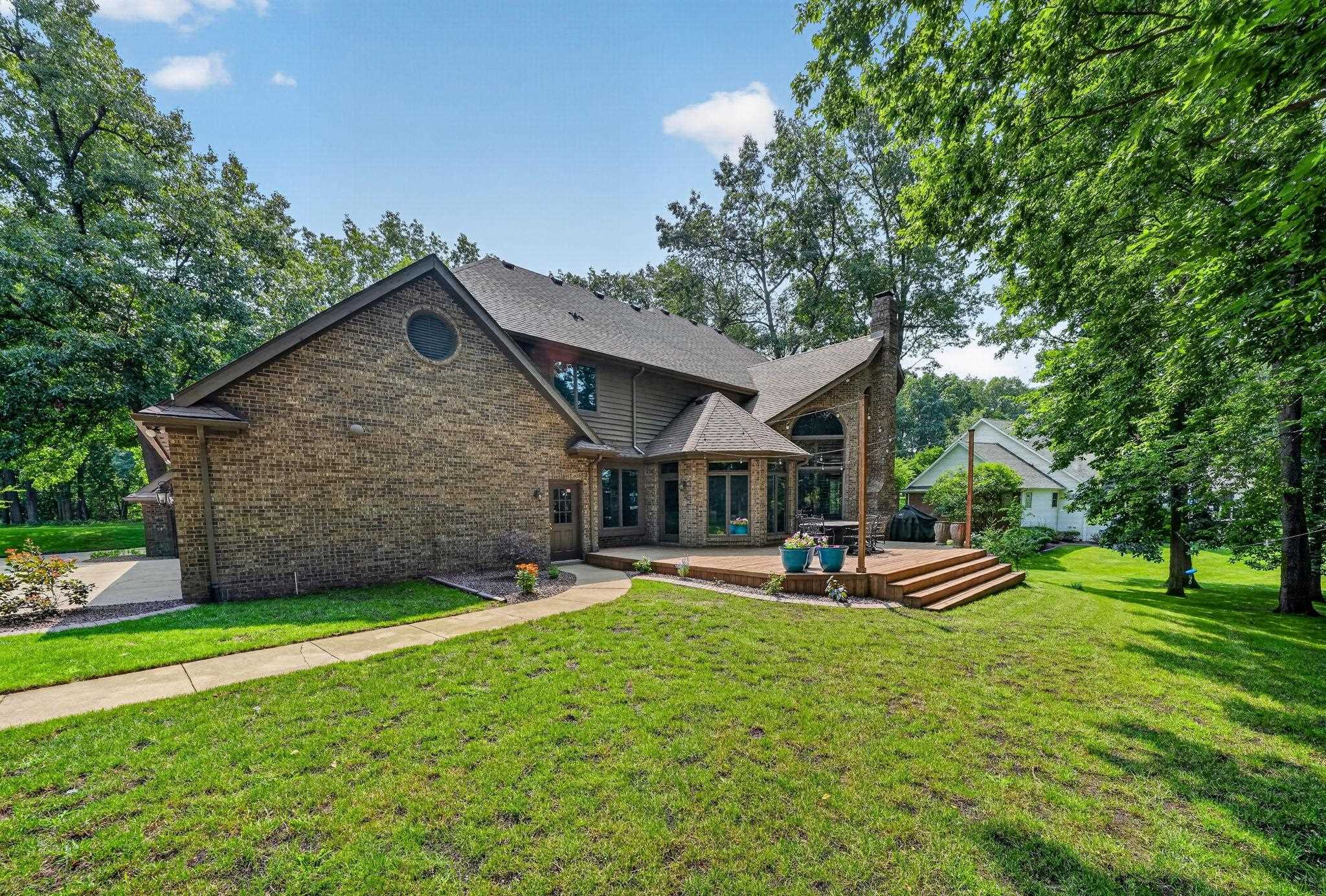 Expansive backyard featuring a multi-level wood deck with stairs, surrounded by mature trees