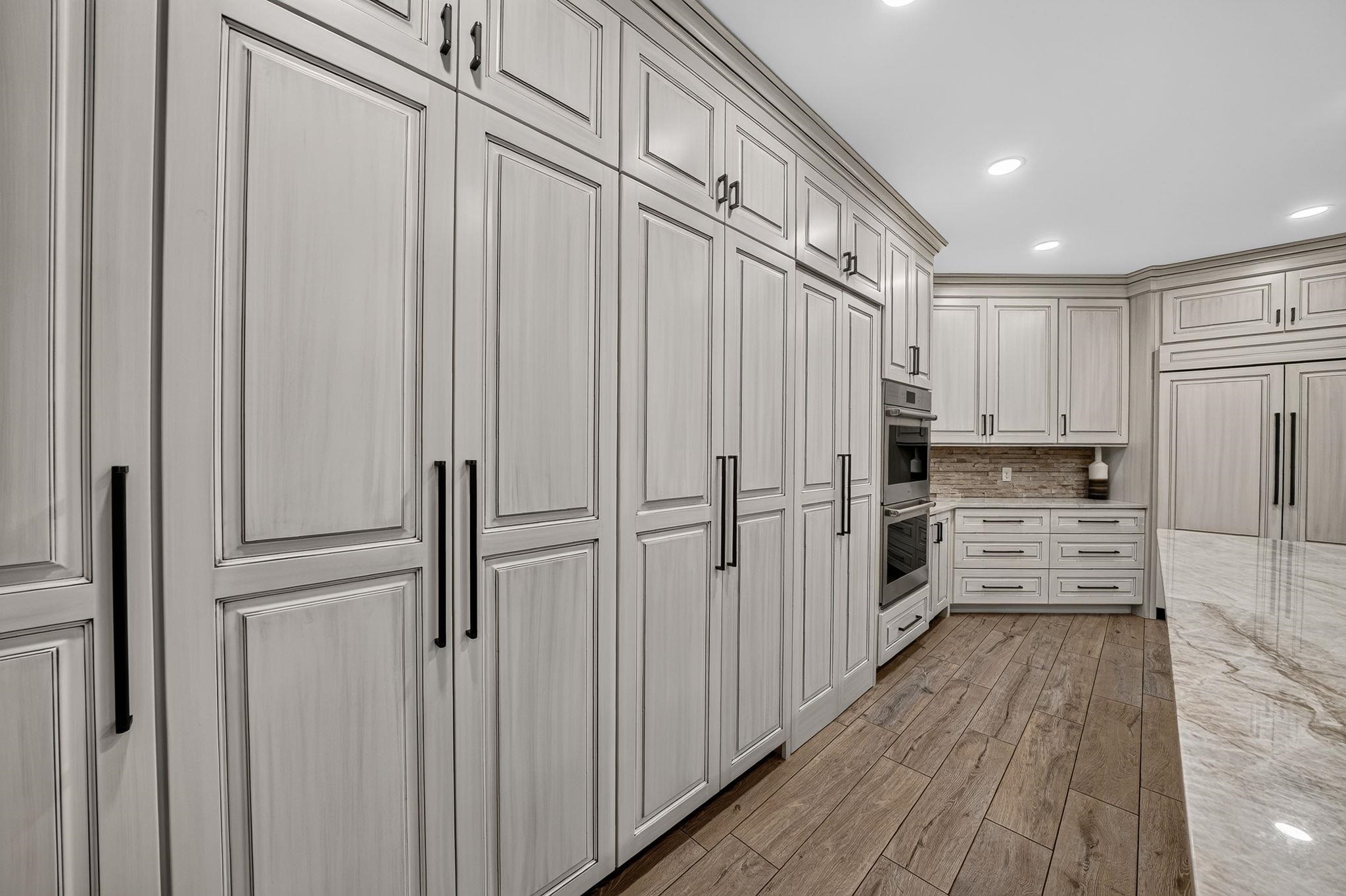 Extensive custom cabinetry with a distressed light finish and matte black hardware
