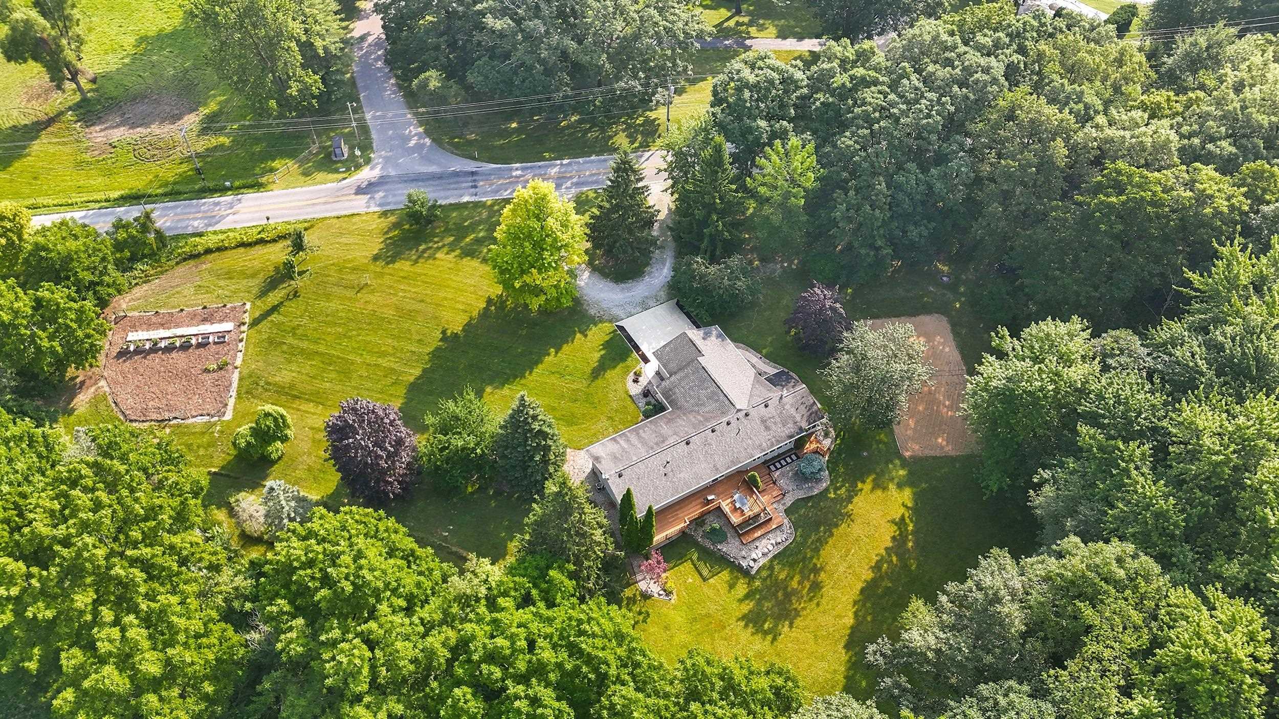 Expansive property featuring a multi-level structure, a large wooden deck, and extensive tree coverage
