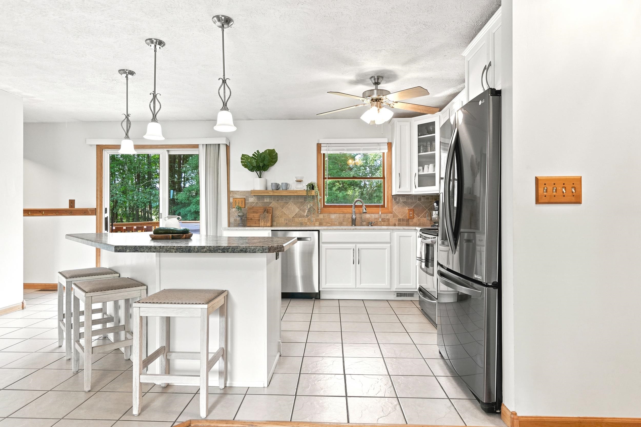Kitchen featuring a central island with a granite-style countertop, white cabinetry, stainless steel appliances, and tile flooring