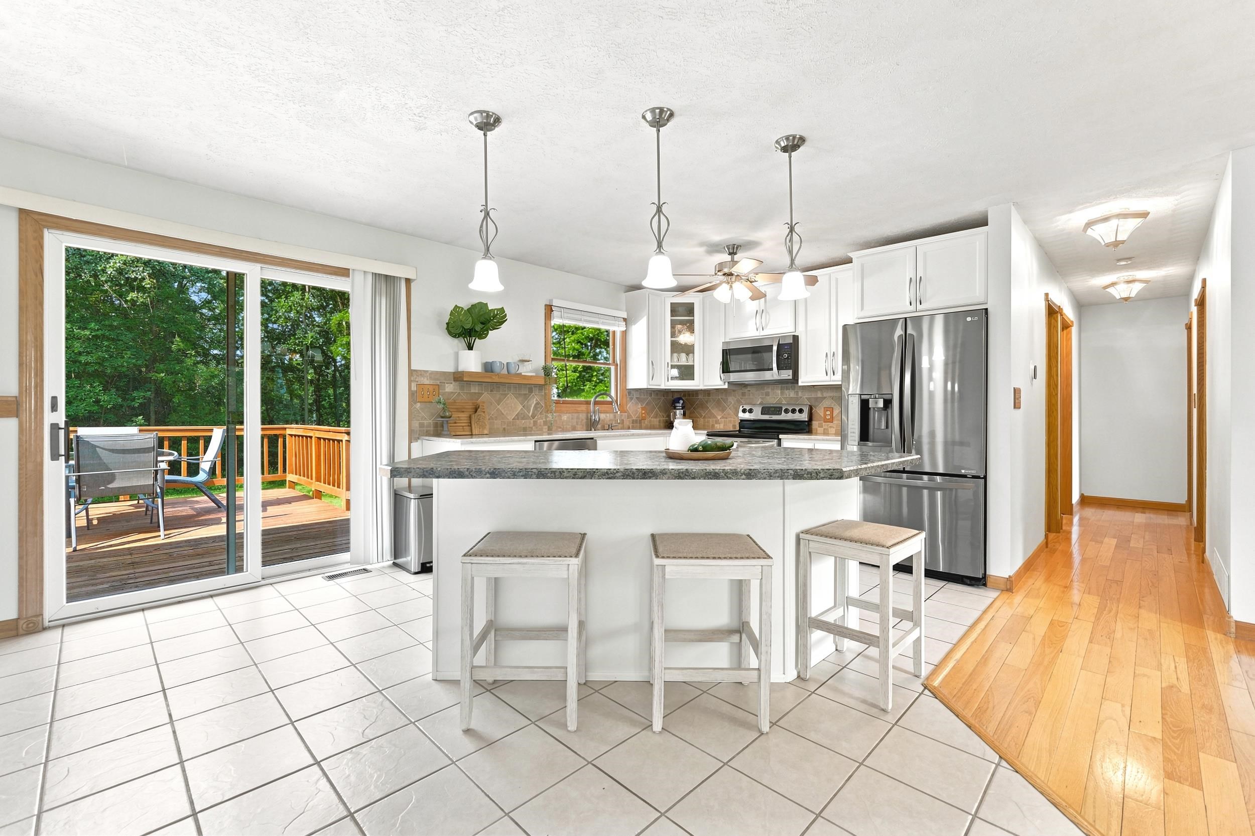 Spacious kitchen featuring an island with pendant lighting, white cabinetry, stainless steel appliances, and a tiled backsplash