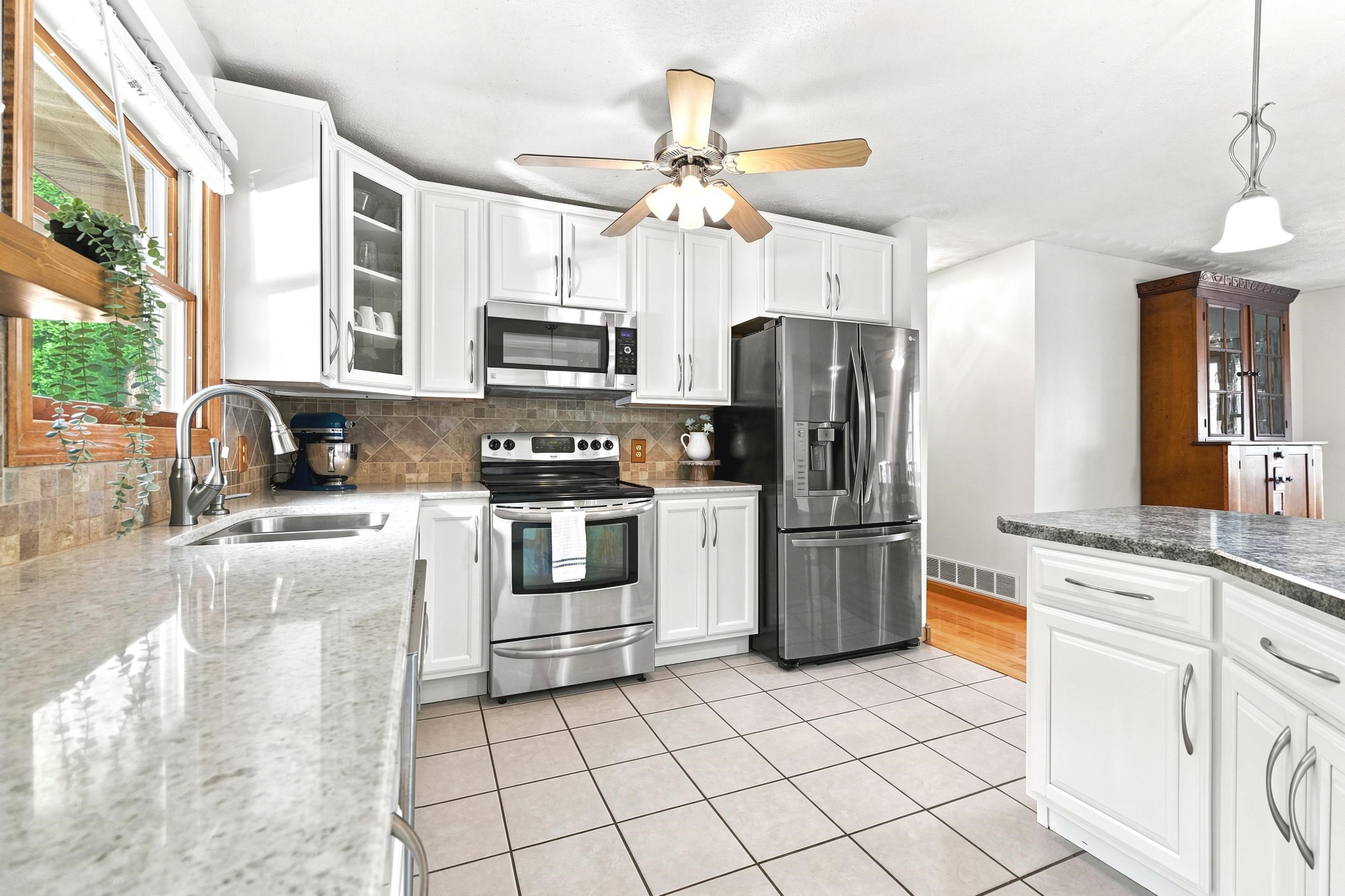 Bright kitchen featuring white cabinetry, stainless steel appliances, a tile backsplash, and light-toned countertops