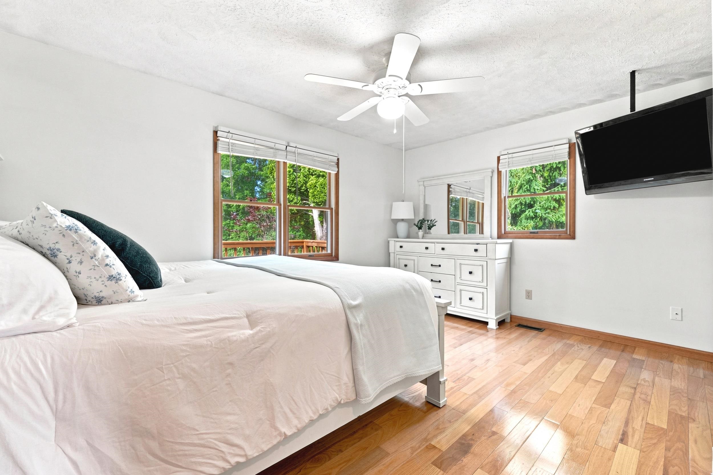 Hardwood-style flooring throughout, white walls, and a ceiling fan with integrated lighting