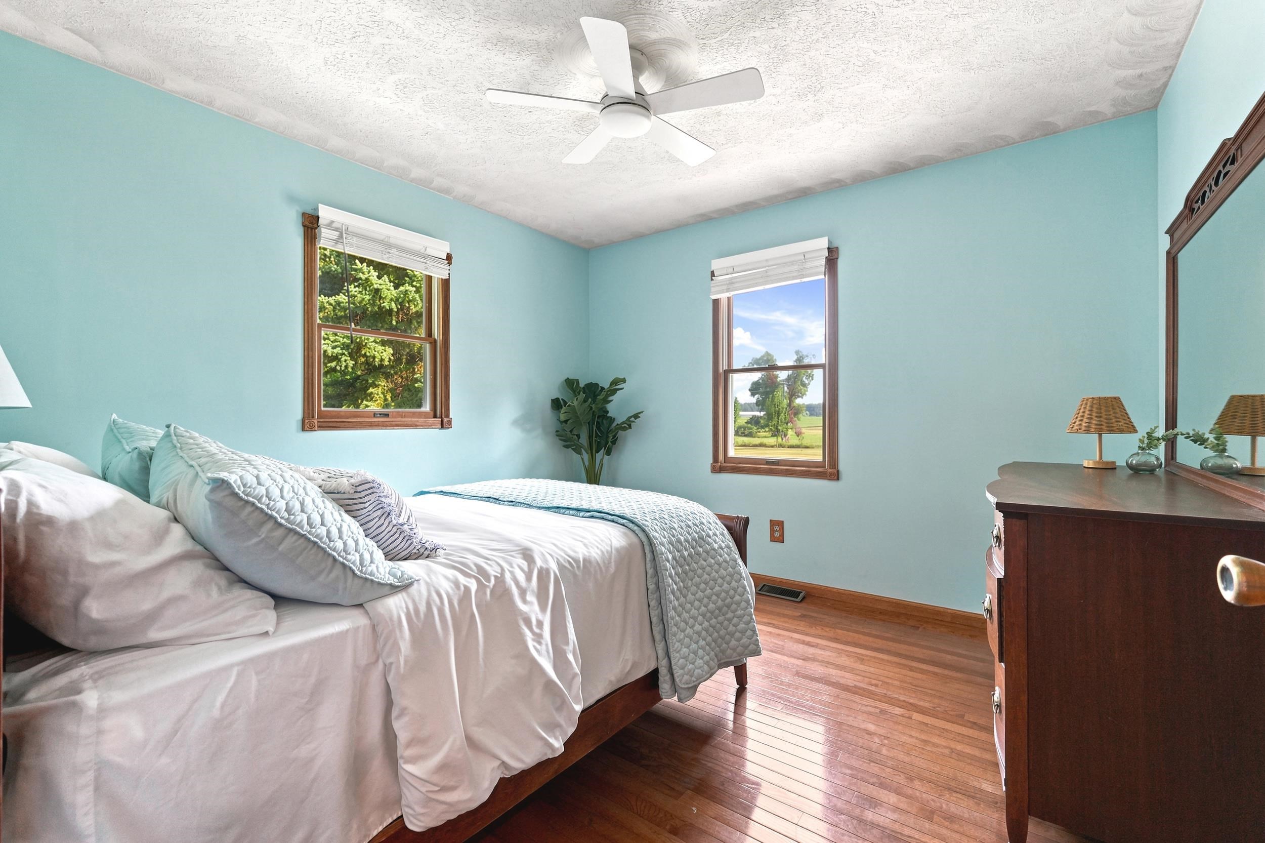 Hardwood flooring throughout featuring two large windows with natural wood trim