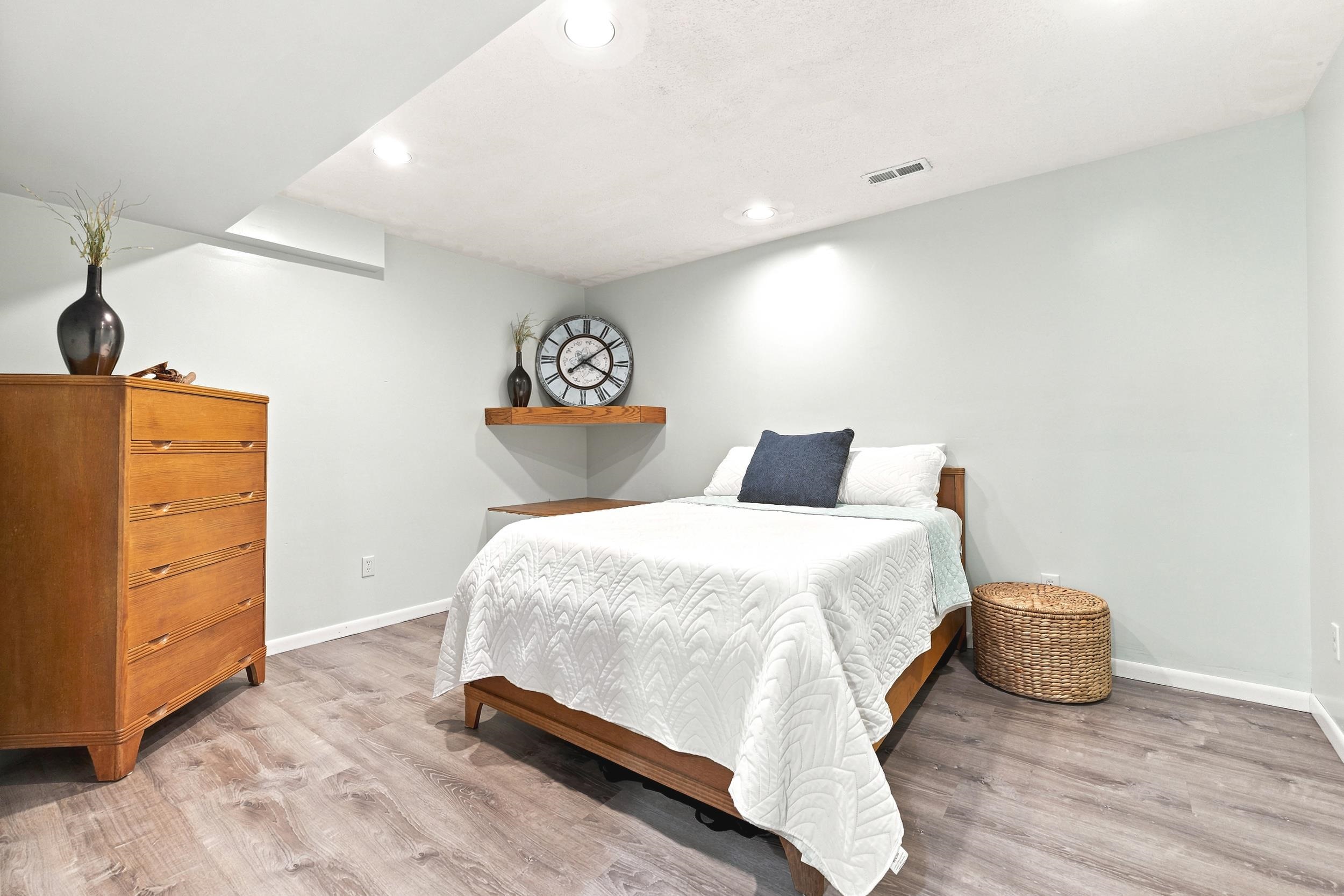 Recessed lighting illuminates this room featuring wood-finish flooring and light-toned walls
