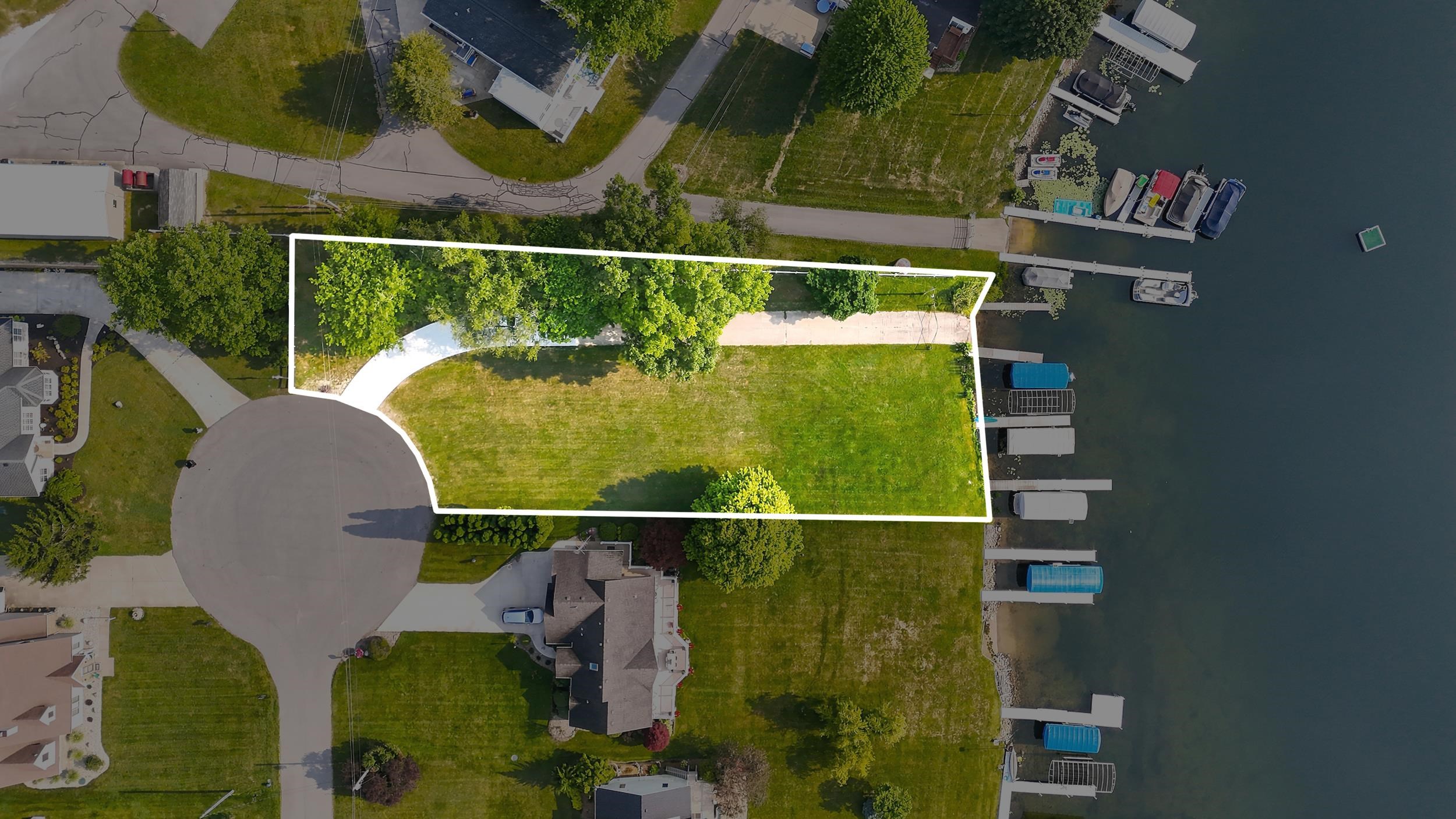 Expansive waterfront lot featuring a broad grassy area and mature trees