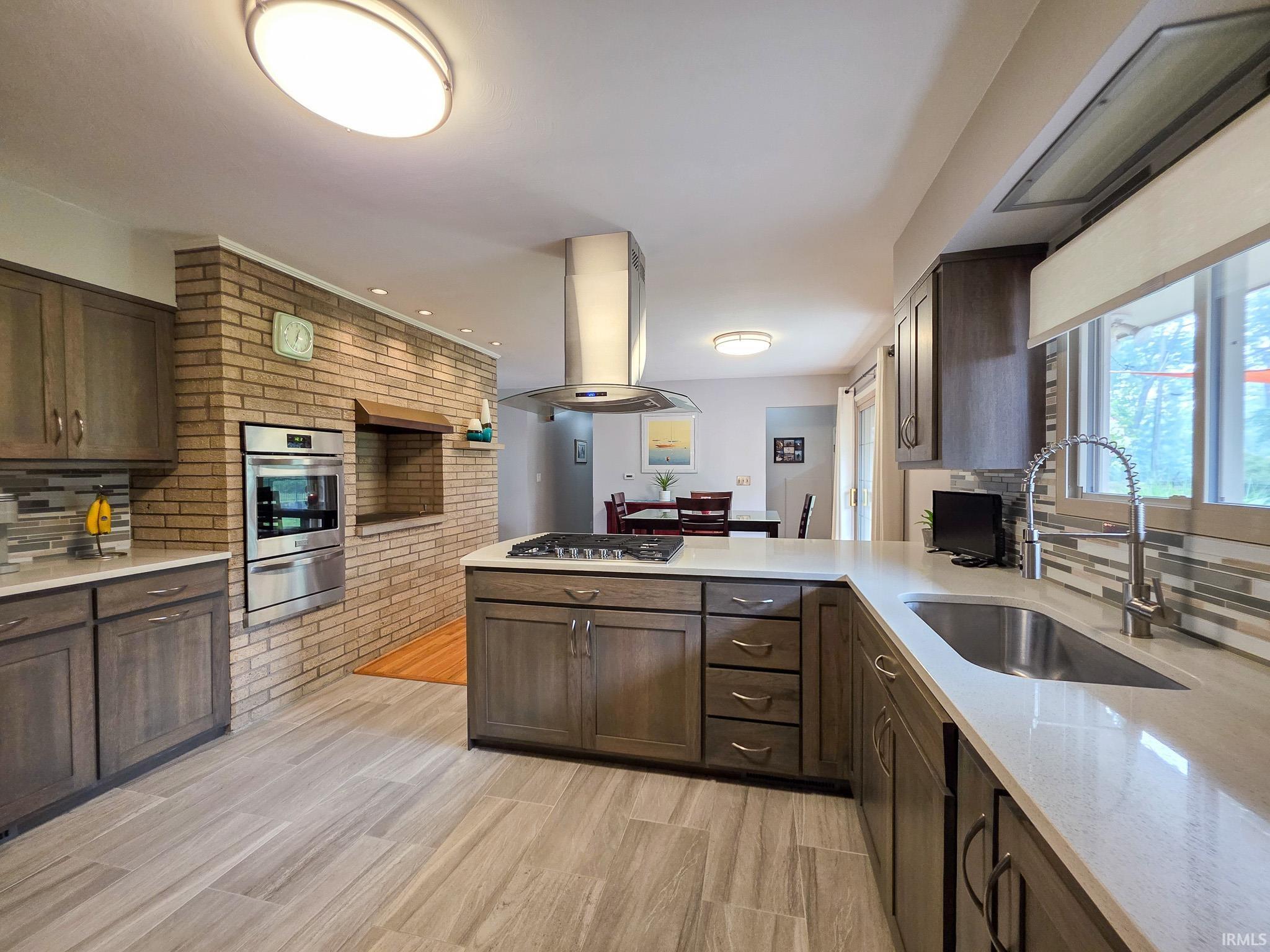 Contemporary kitchen featuring wood-finish cabinetry, Quartz countertops and a tiled backsplash
