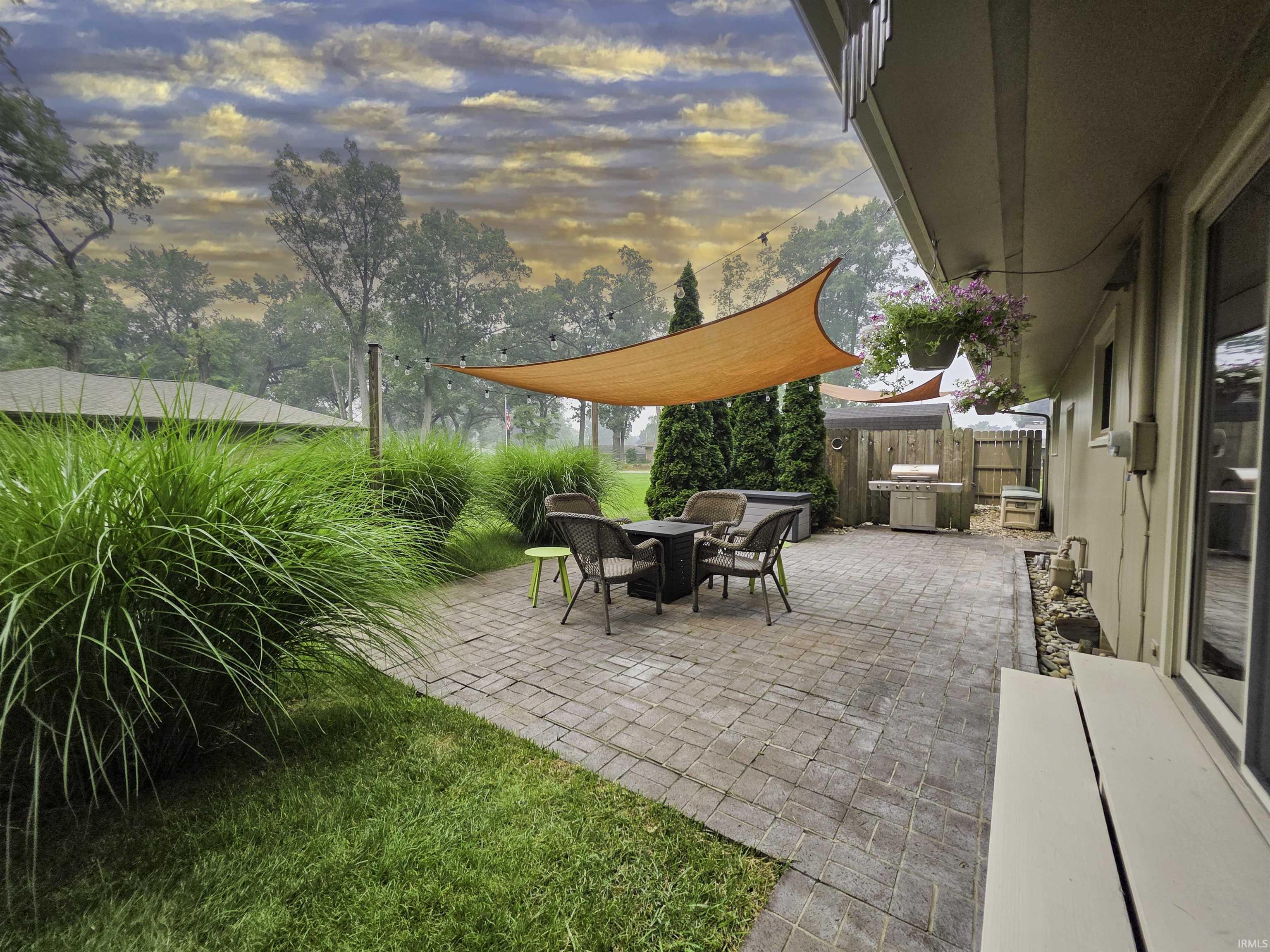 Expansive paver patio featuring a shade sail and string lighting