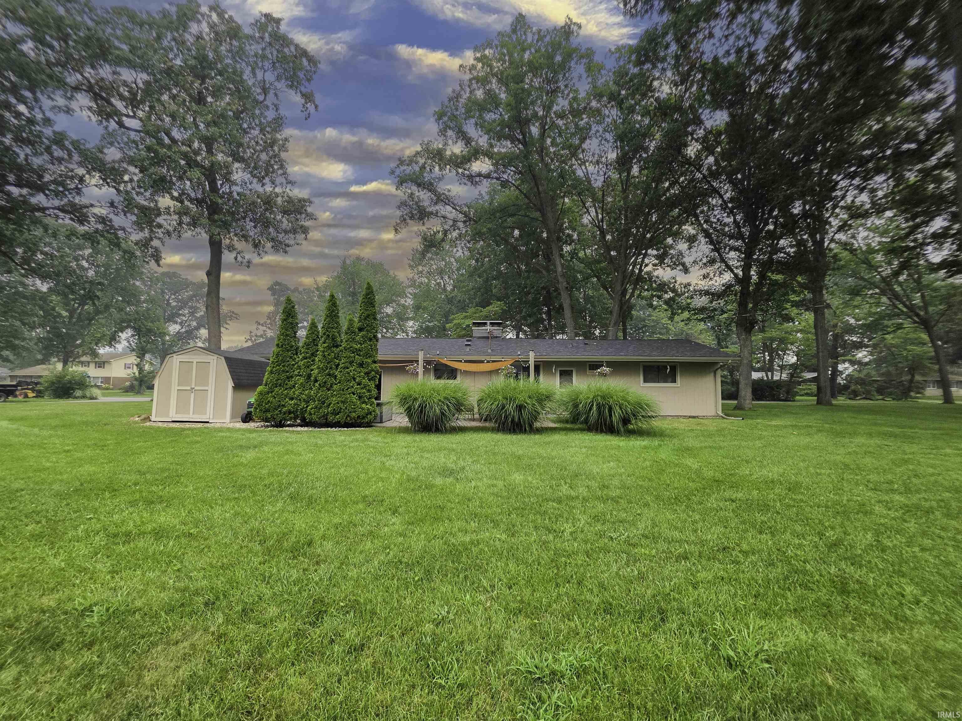 Expansive green lawn with mature trees and a detached shed