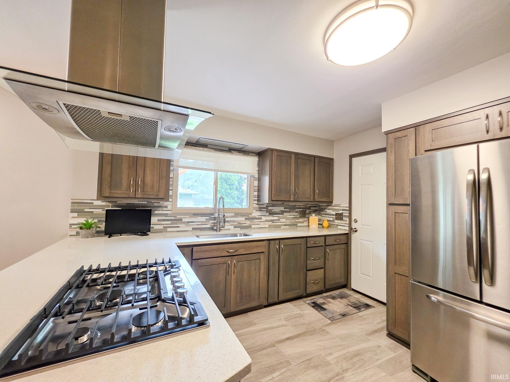 Kitchen featuring a gas cooktop with stainless steel range hood, tile flooring, and stainless steel appliances