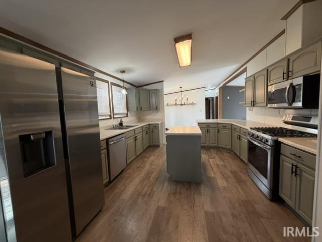 Spacious kitchen featuring stainless steel appliances, wood-finish flooring, a central island, light-toned cabinetry, and white countertops