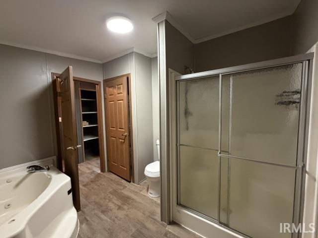 Bathroom featuring a jetted tub, enclosed shower, wood-finish flooring, and a recessed ceiling light