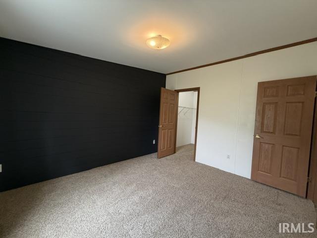 Bedroom featuring a dark accent wall with horizontal paneling, light-colored walls, wood-grain interior doors, and carpet flooring