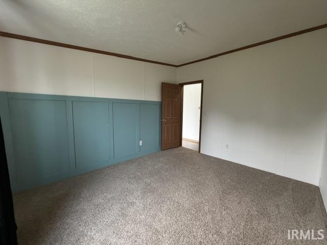 Bedroom featuring a blue board and batten accent wall, neutral wall panels, and brown trim