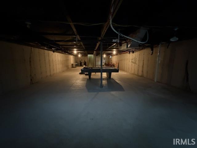 Expansive basement featuring exposed concrete walls and flooring