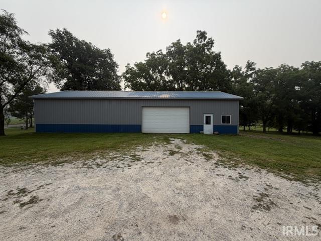 Spacious outbuilding featuring a metal roof, two-tone siding, a roll-up garage door, an entry door, and two windows