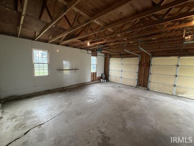 Spacious garage structure featuring exposed wood ceiling joists and plywood sheathing
